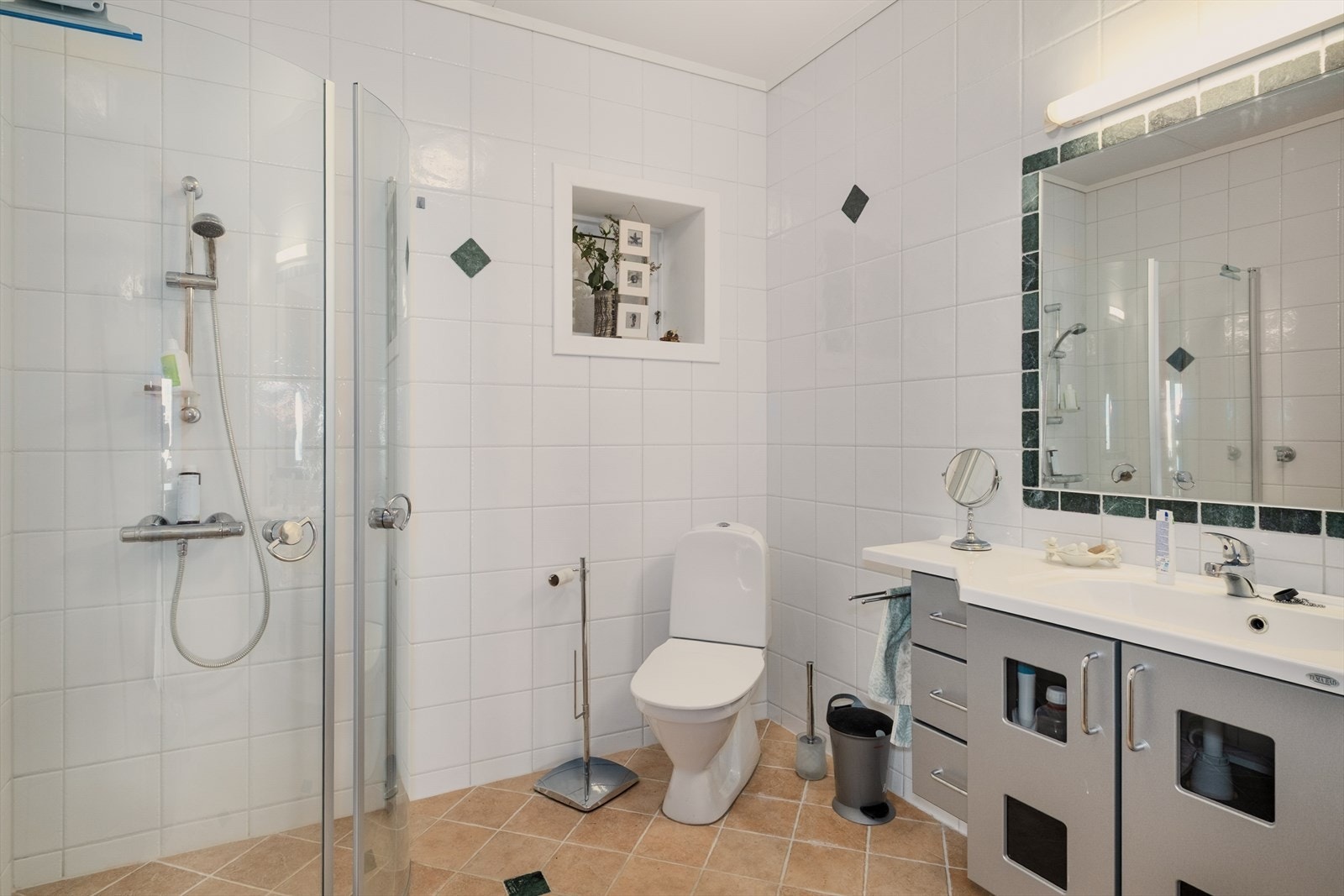 Bad i leiligheten fra ca. 2000, med fliser, vannbåren varme og opplegg for vaskemaskin. Galleribilde