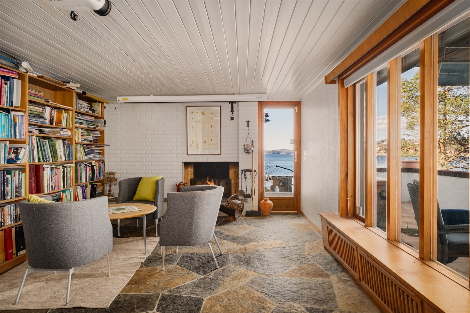 Kjellerstue på 29,4 m² med skifergulv, peis og utgang til terrasse. . Galleribilde
