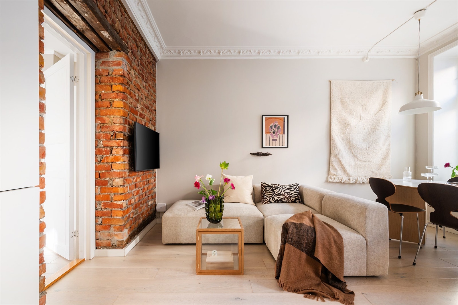 En eksponert teglsteinsvegg gir stuen en rustikk og stilig kontrast til de ellers moderne overflatene. Galleribilde