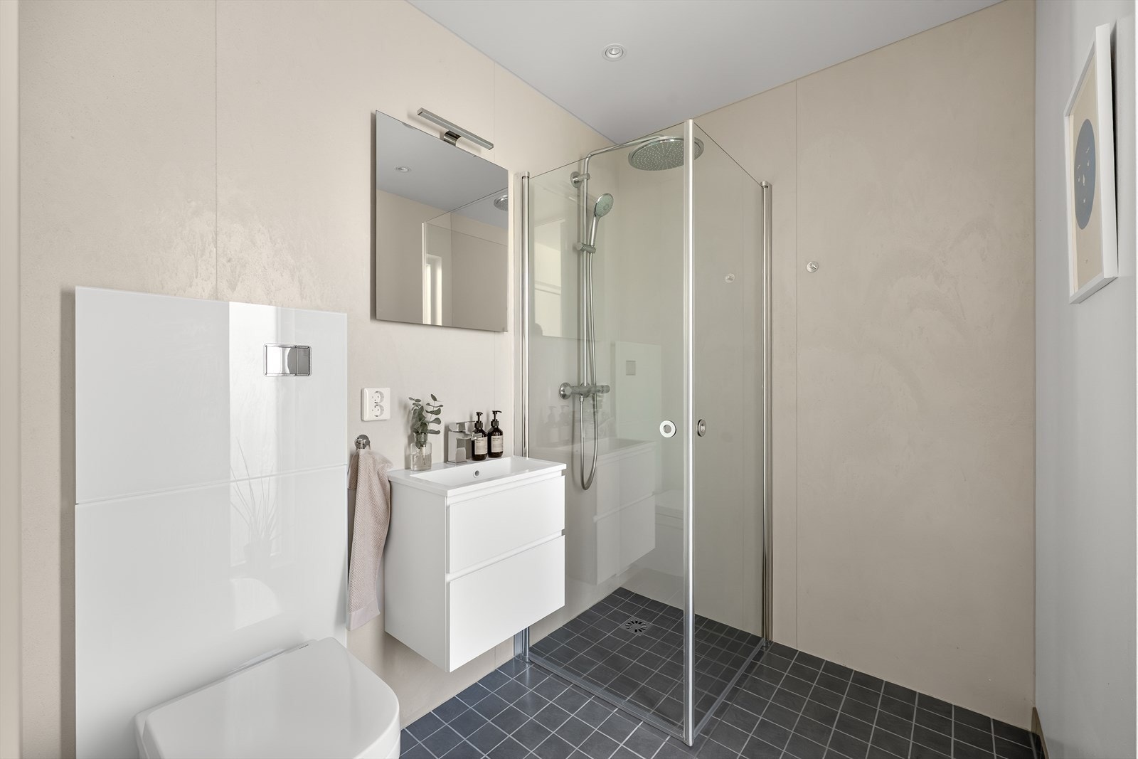 Badet i første etasje har flislagt gulv med vannbåren varme, vegghengt toalett og dusjhjørne med innsvingbare glassdører. Galleribilde