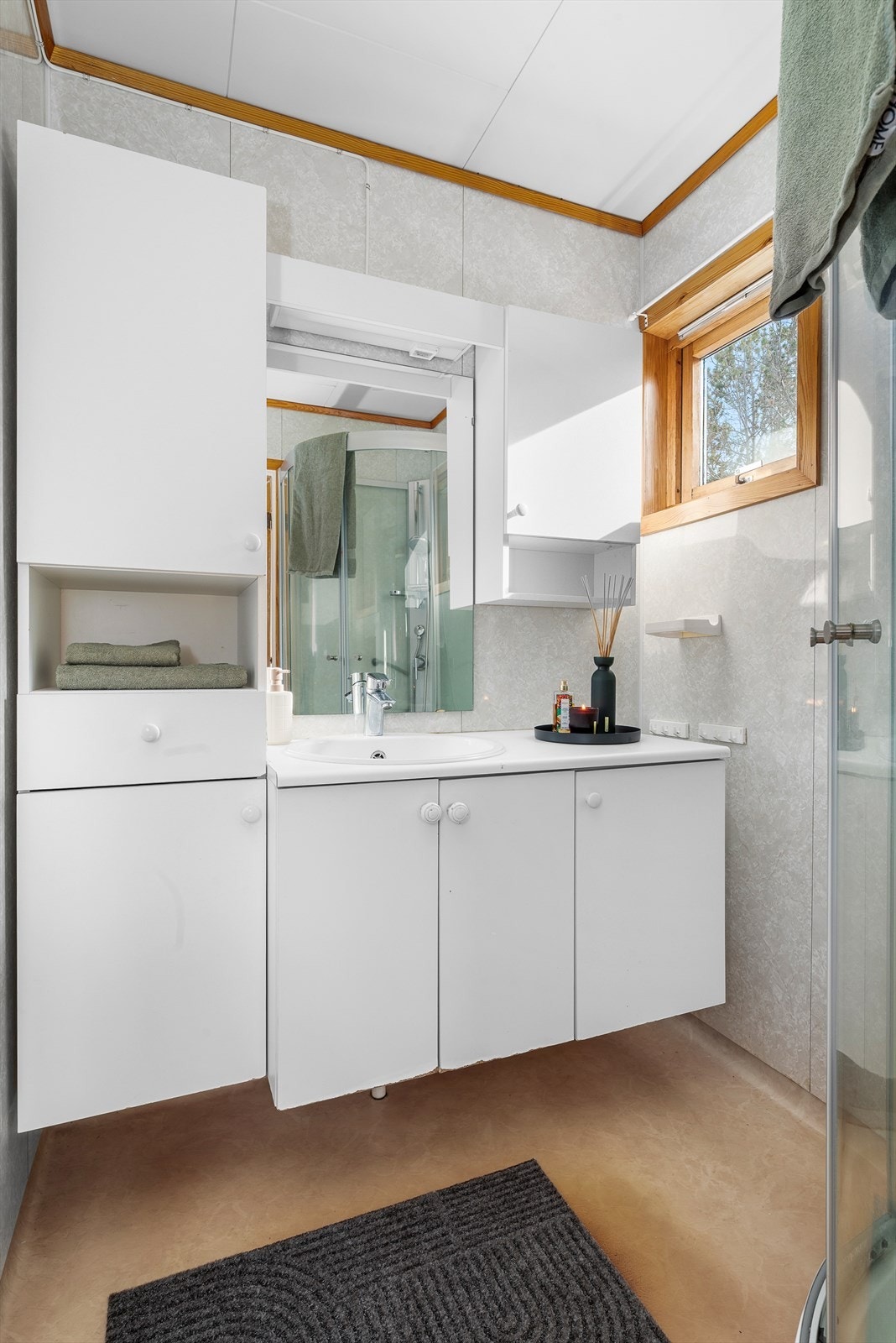 Badet er utstyrt med servantinnredning, skap, dusjhjørne og toalett. Galleribilde