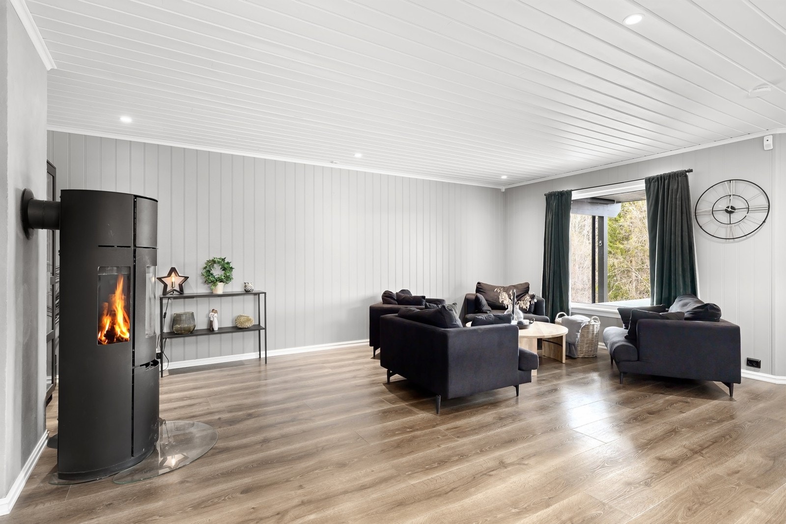 Innbydende og innholdsrik stue med 1-stavs laminat på gulv og malt panel på vegger, malt i en moderne og lun fargetone. Galleribilde
