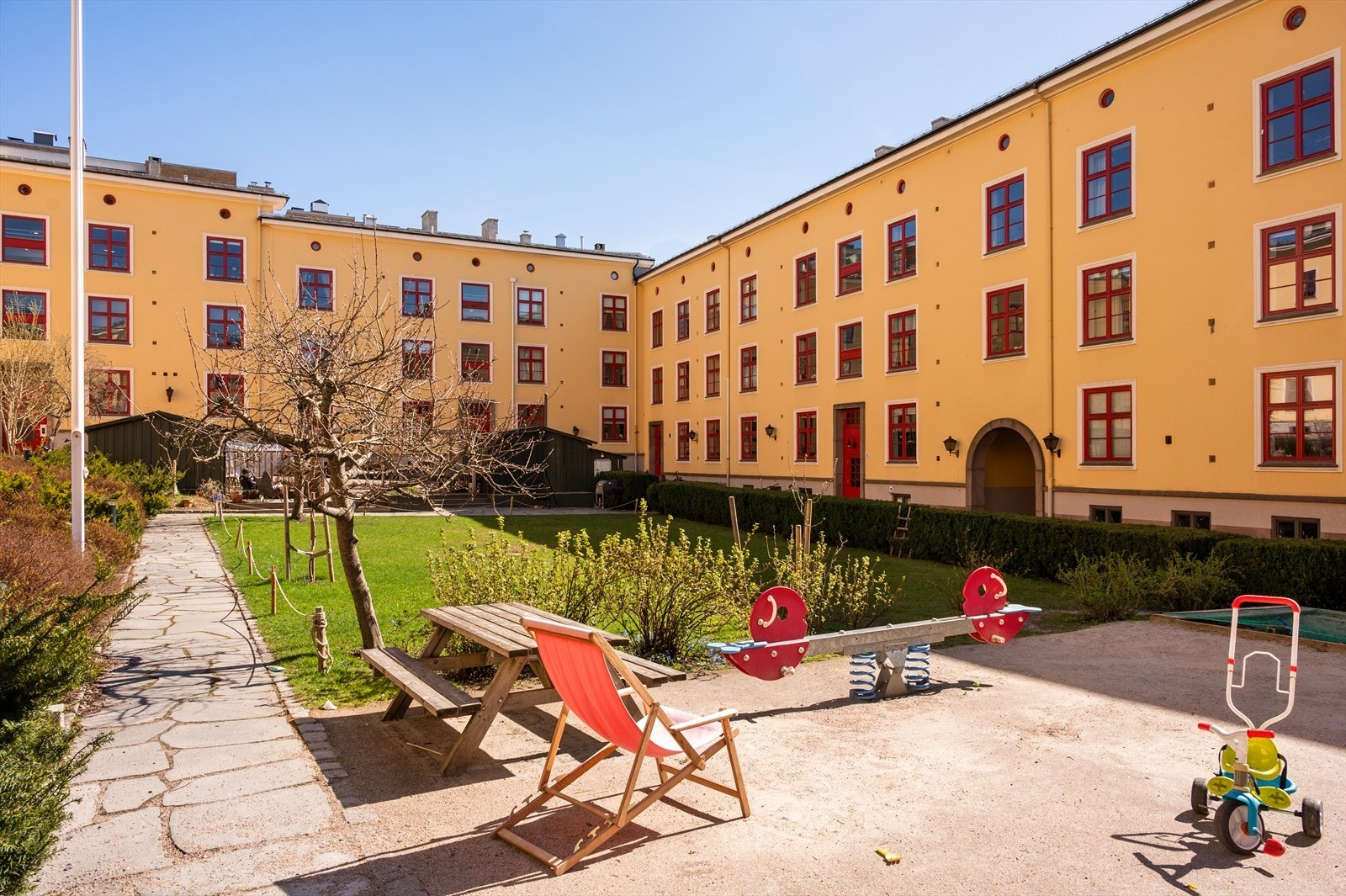 Hyggelig felles bakgård med gressplen, lekestativ og sykkelbod - et skjermet uteområde hvor du kan nyte solrike dager med familie og venner. Galleribilde