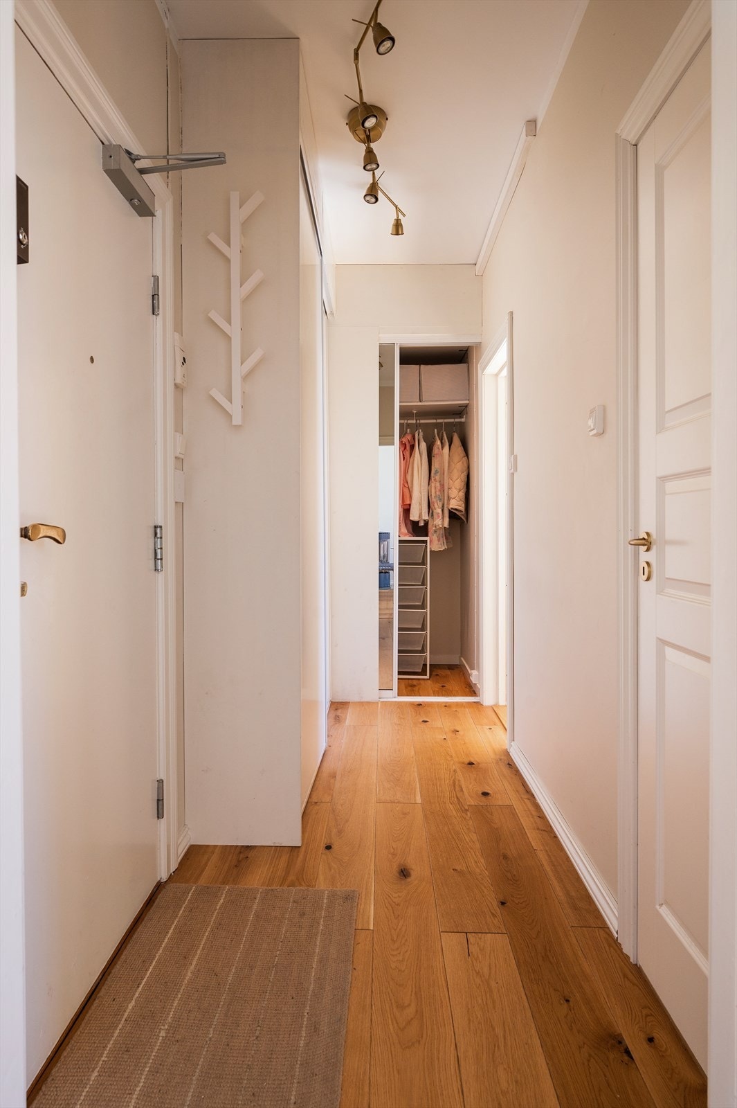 Lys og praktisk entré med tregulv, knaggrekker og garderobe for hverdagslige behov - god oppbevaringsplass og gjennomgang til de andre rommene. Galleribilde