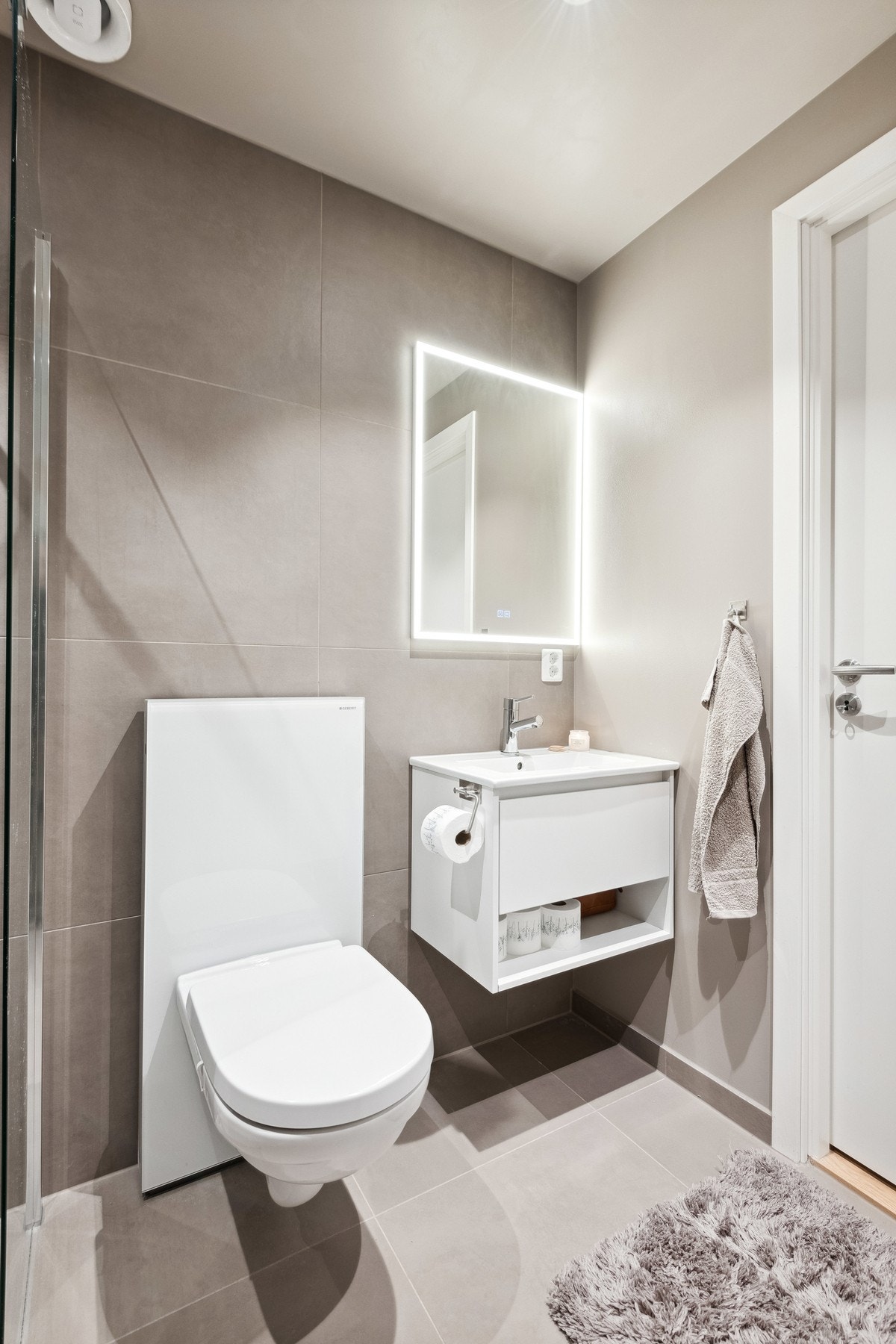 Badet har lune fargevalg med vegghengt toalett og flislagt gulv med varmekabler. Galleribilde