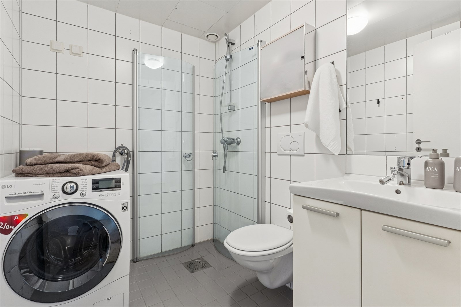 Flislagt baderom fra 2005 med elektriske varmekabler i gulv og malt himling. Badet er utstyrt med speil, servantskap, vegghengt toalett, servant og dusj med glassdører. Det er plass og opplegg for vaskemaskin. Badet har mekanisk avtrekk. Galleribilde