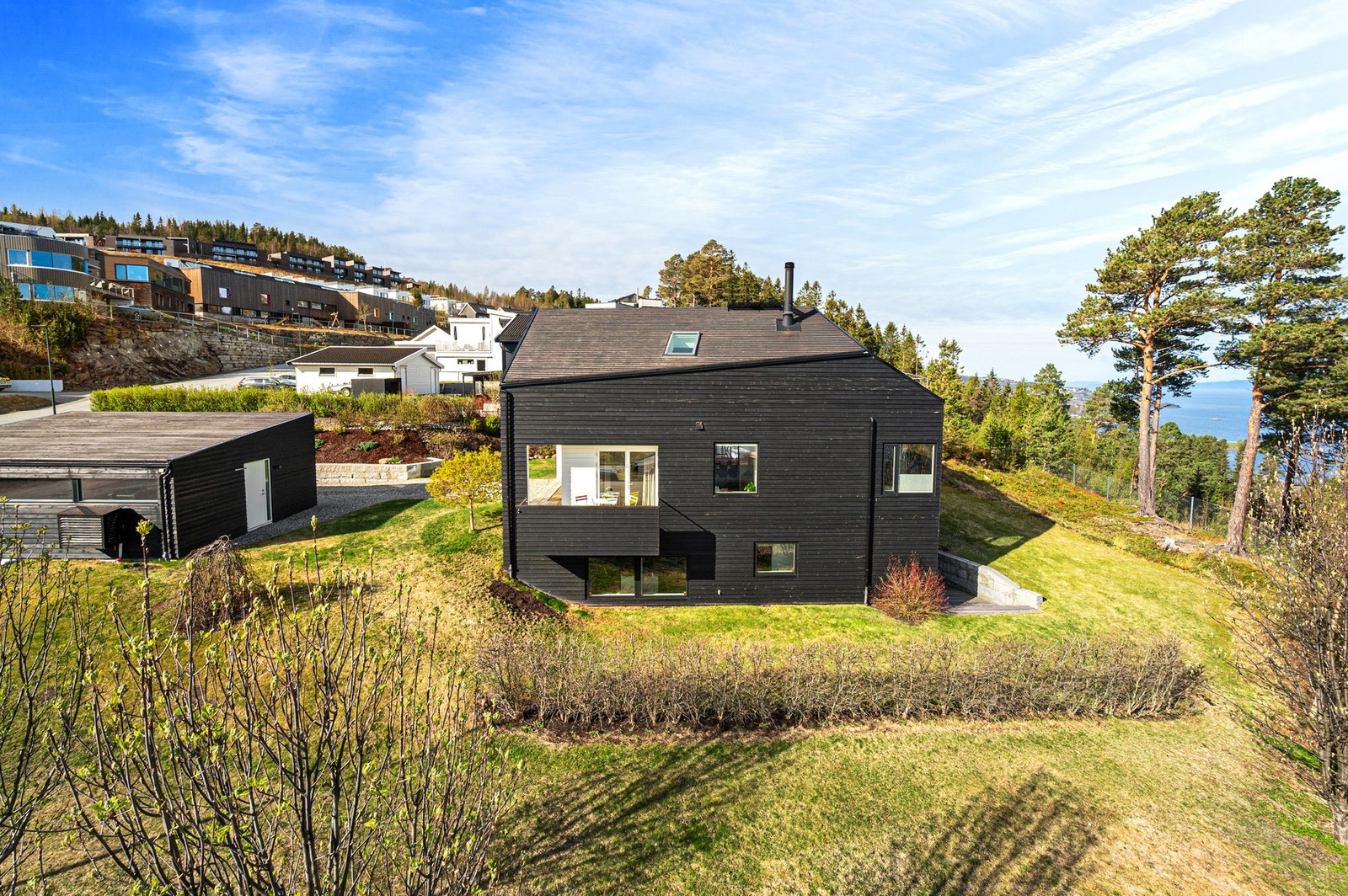 Hage rundt hele huset - fra oversiden ved den største uteplassen/terrassen, videre rundt fremsiden og rundt mot garasjen igjen. Tett og fin hekk som grenser mot velforeningens tomt. Galleribilde