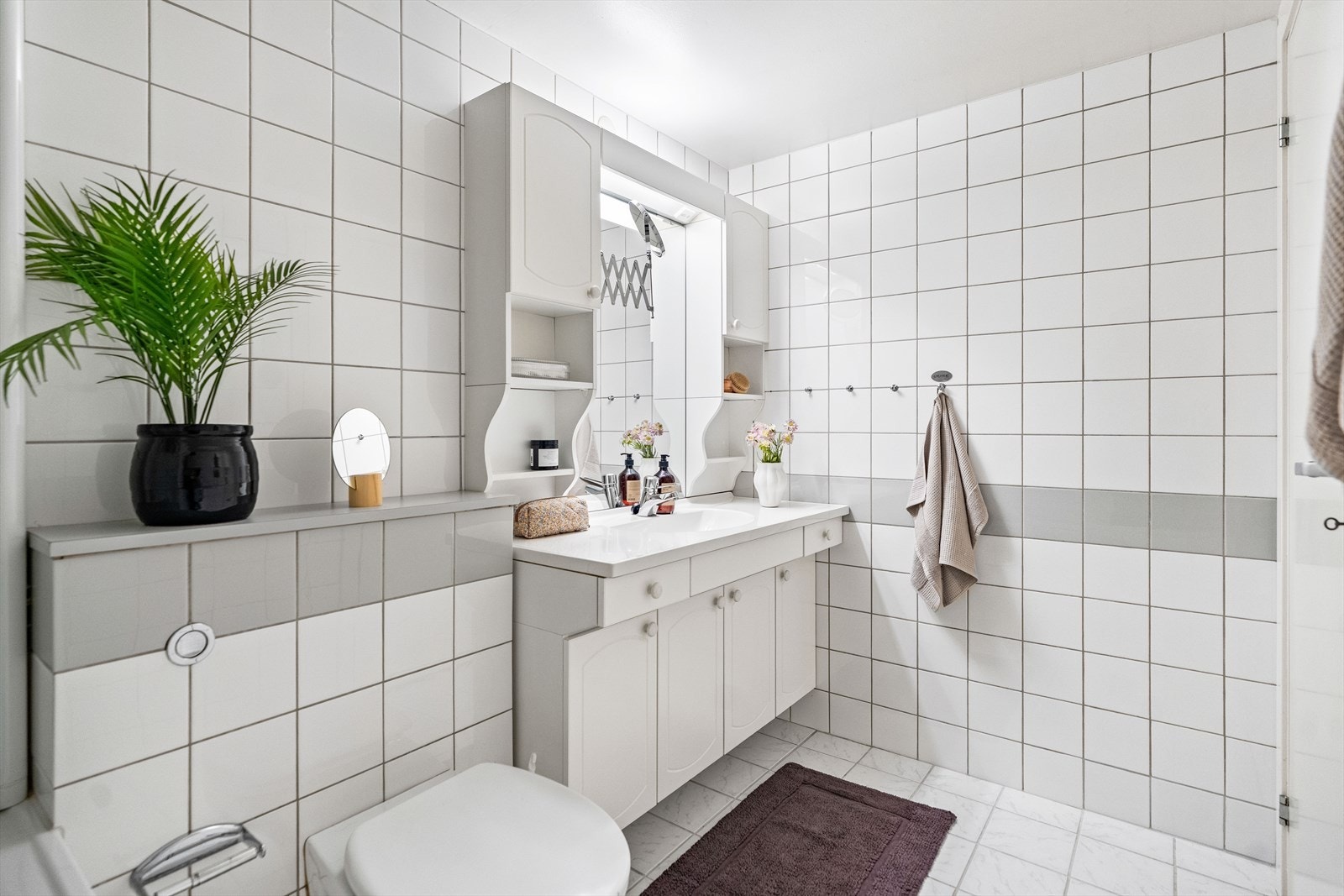 Rommet er utstyrt med baderomsinnredning, servant, veggmontert wc og innmurt badekar. Galleribilde