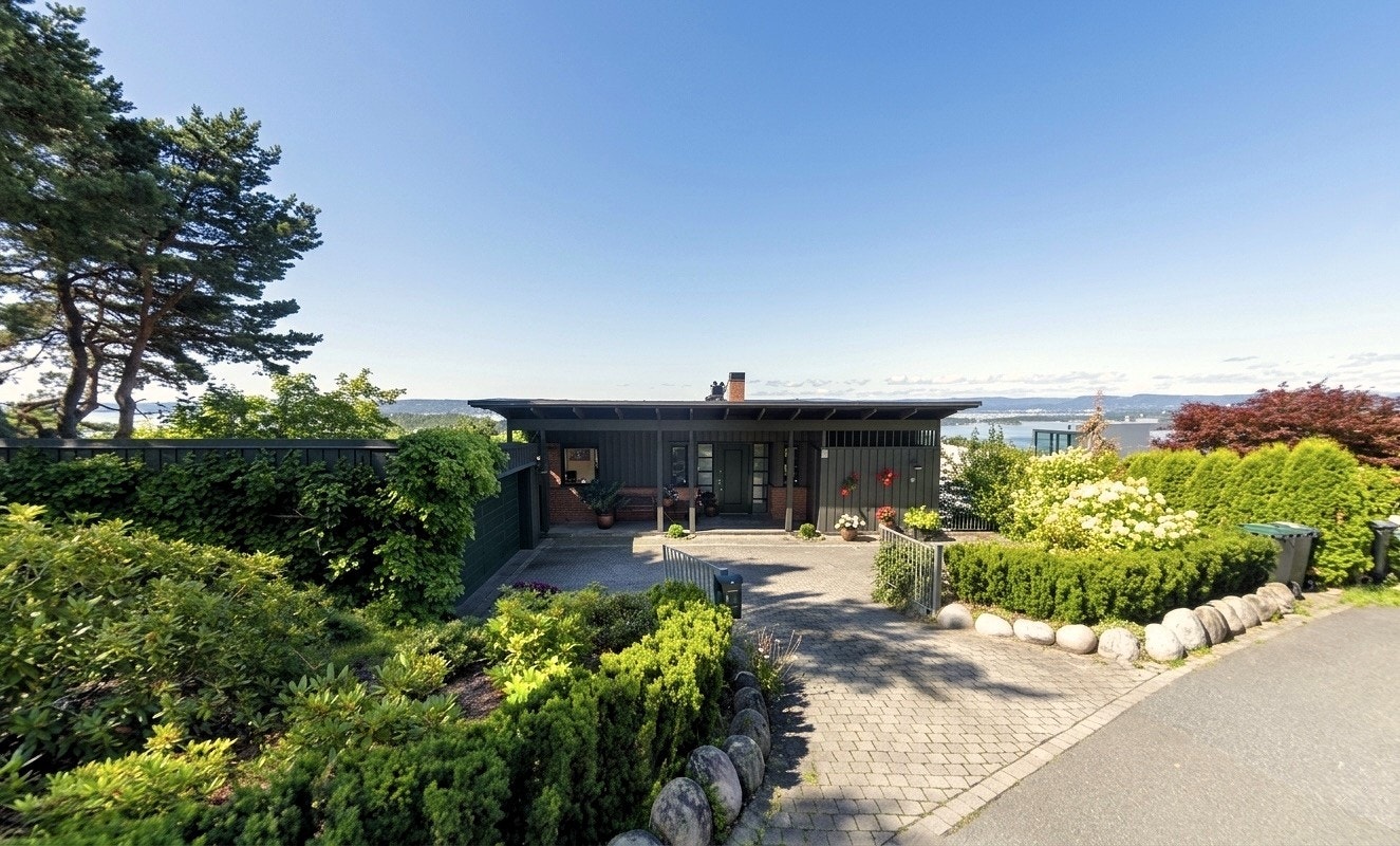 Eiendommens tomt er omkranset av vakker og velstelt beplantning, og en dobbel inngangsport leder deg videre inn til et gjennomført og idyllisk uteområde. Bildet er hentet fra Googlemaps for å vise boligen ved sommertid. Galleribilde