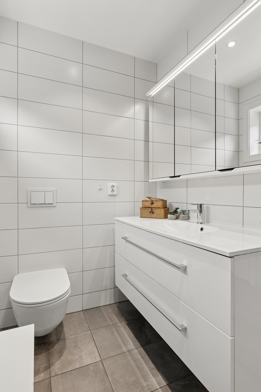 Badet i andre etasje er helfliset og utstyrt med servant i underskap, speil med belysning og vegghengt toalett. Galleribilde