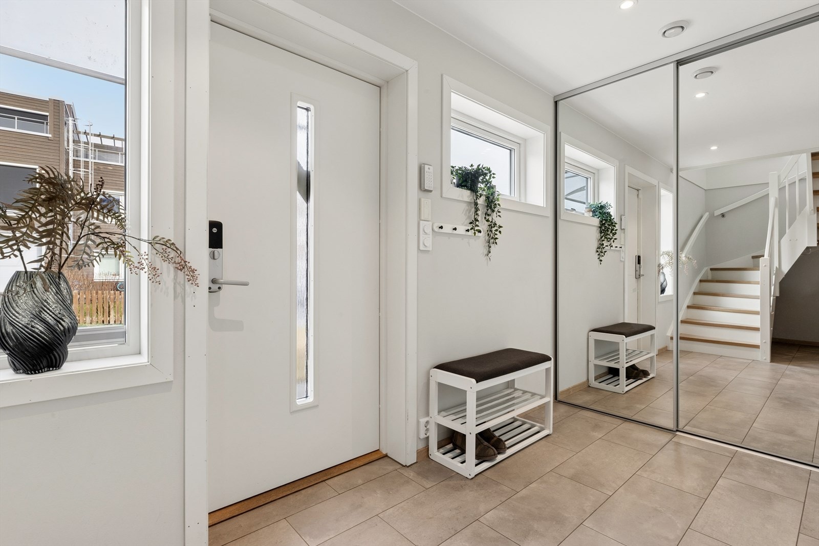 En lys og innbydende entré med flislagt gulv, vannbåren varme og en romslig skyvedørsgarderobe med speilfronter. Galleribilde