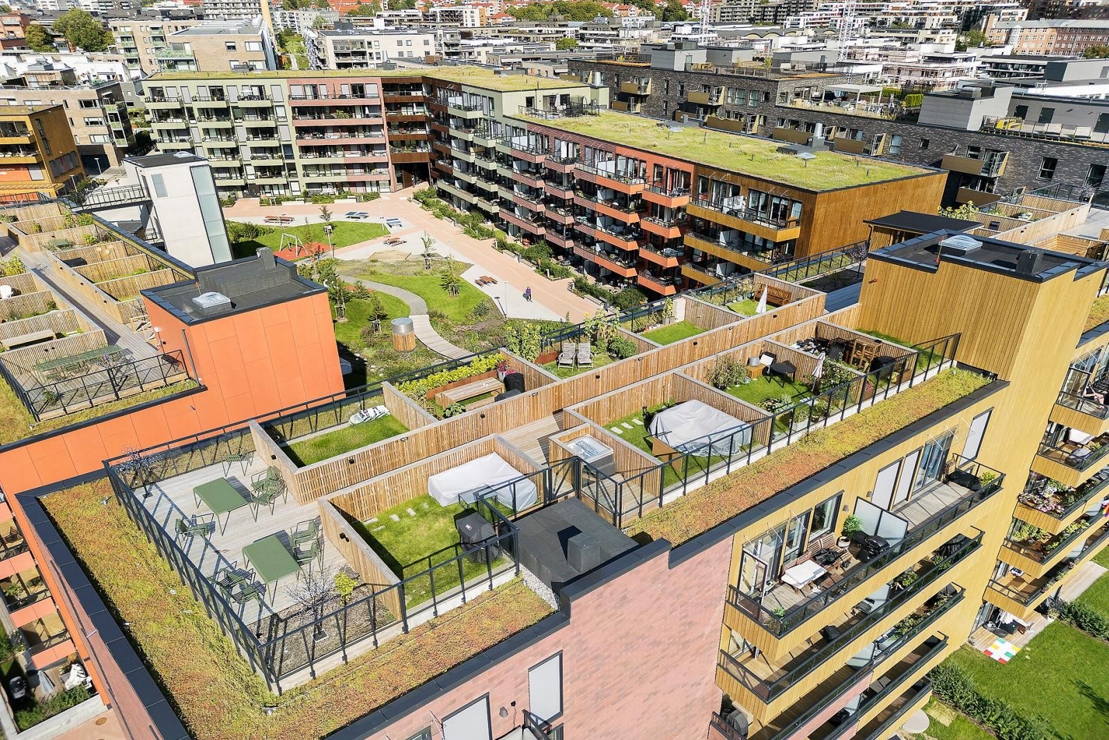 Oversiktsbilde over borettslaget sommerstid med flotte felles takterrasser Galleribilde