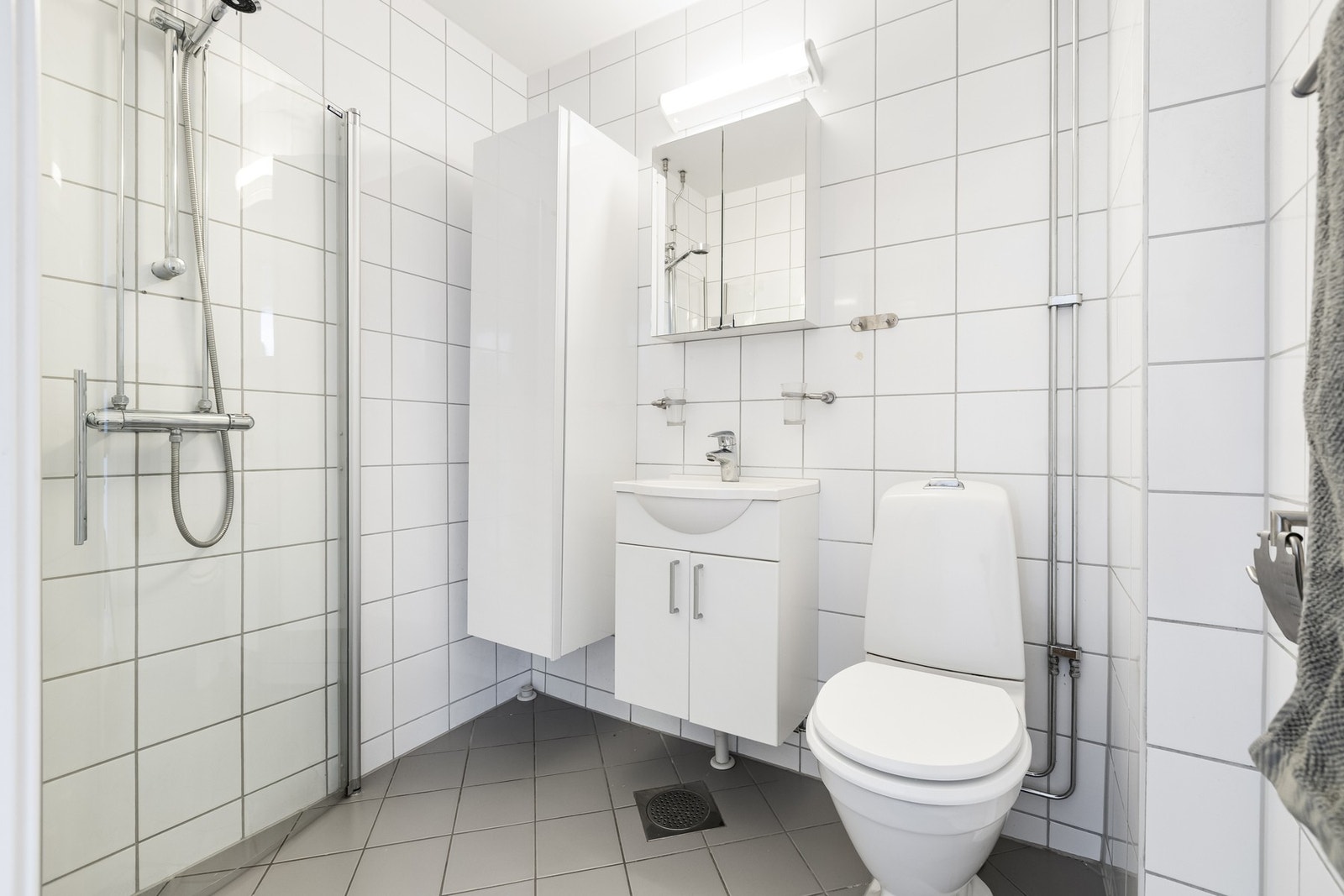Lyst flislagt bad (pusset opp i regi av sameiet i 2008/09). Rommet består av skapinnredning med heldekkende, nedfelt servant, gulvmontert toalett og dusjhjørne med innfellbare dusjvegger. Galleribilde