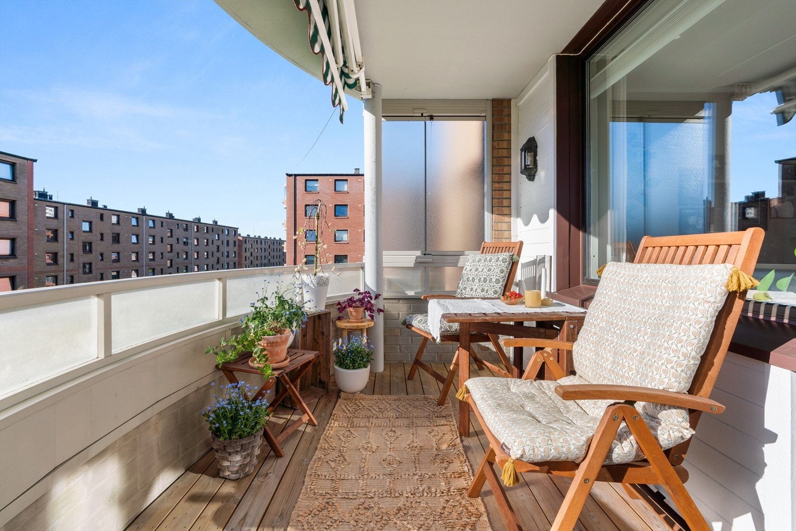 En solrik balkong med terrassebord og et stilrent rekkverk i teglstein med glassfelter gir et trivelig og skjermet uterom. Galleribilde