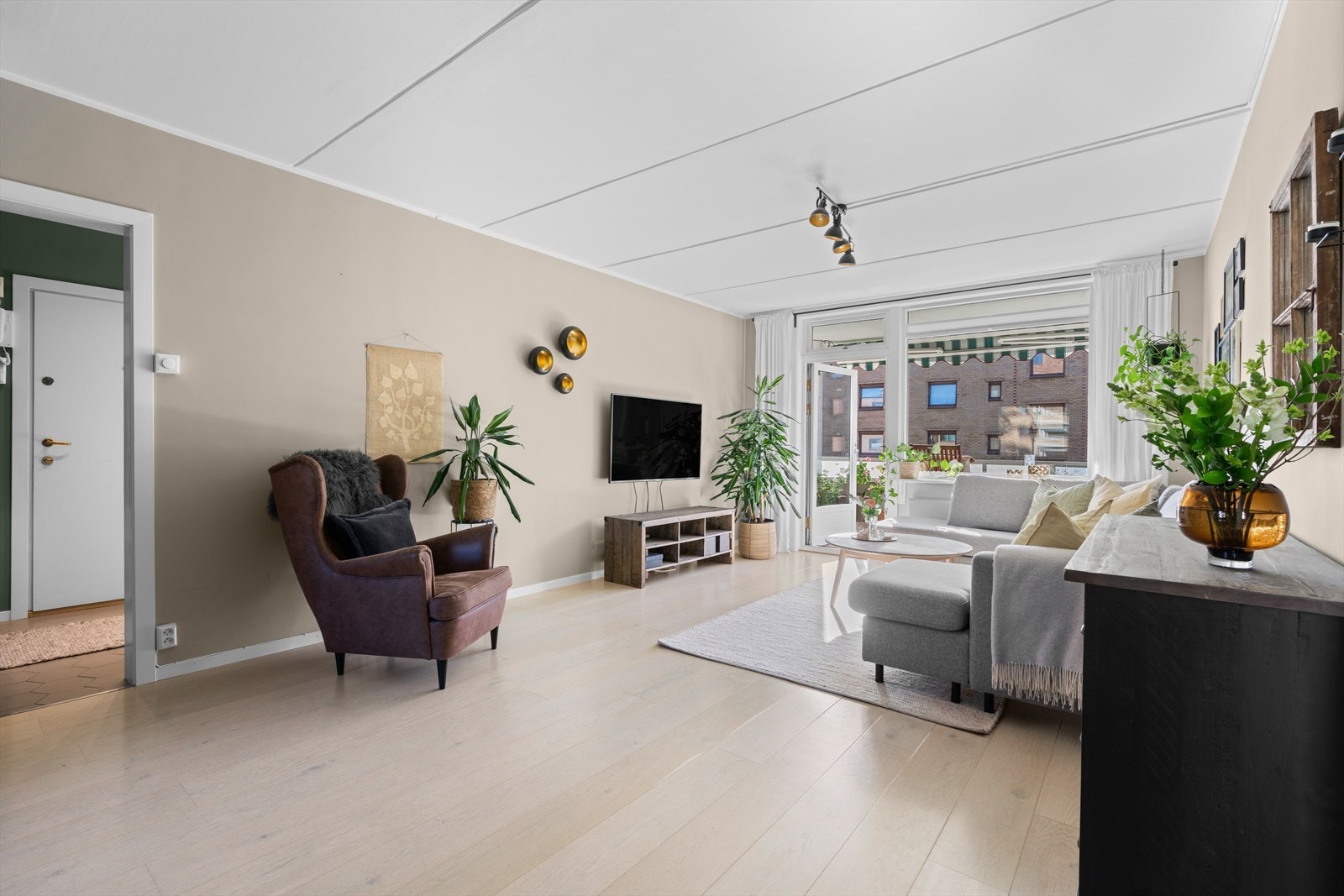 Store vindusflater og utgang til balkong gir rikelig med naturlig lys inn i stuen. Galleribilde