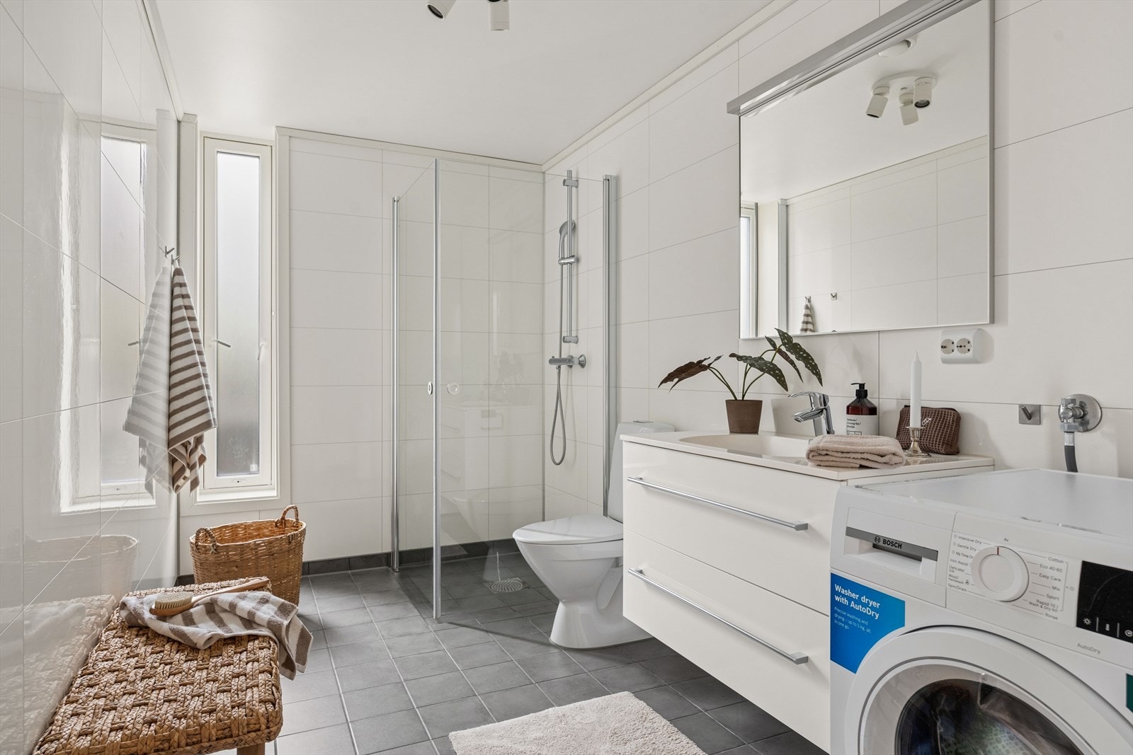 Badet er av god størrelse og tidløst innredet med grå fliser på gulvet og hvite baderomsplater på vegg. I gulvet har man også vannbåren gulvvarme for ekstra komfort. Galleribilde