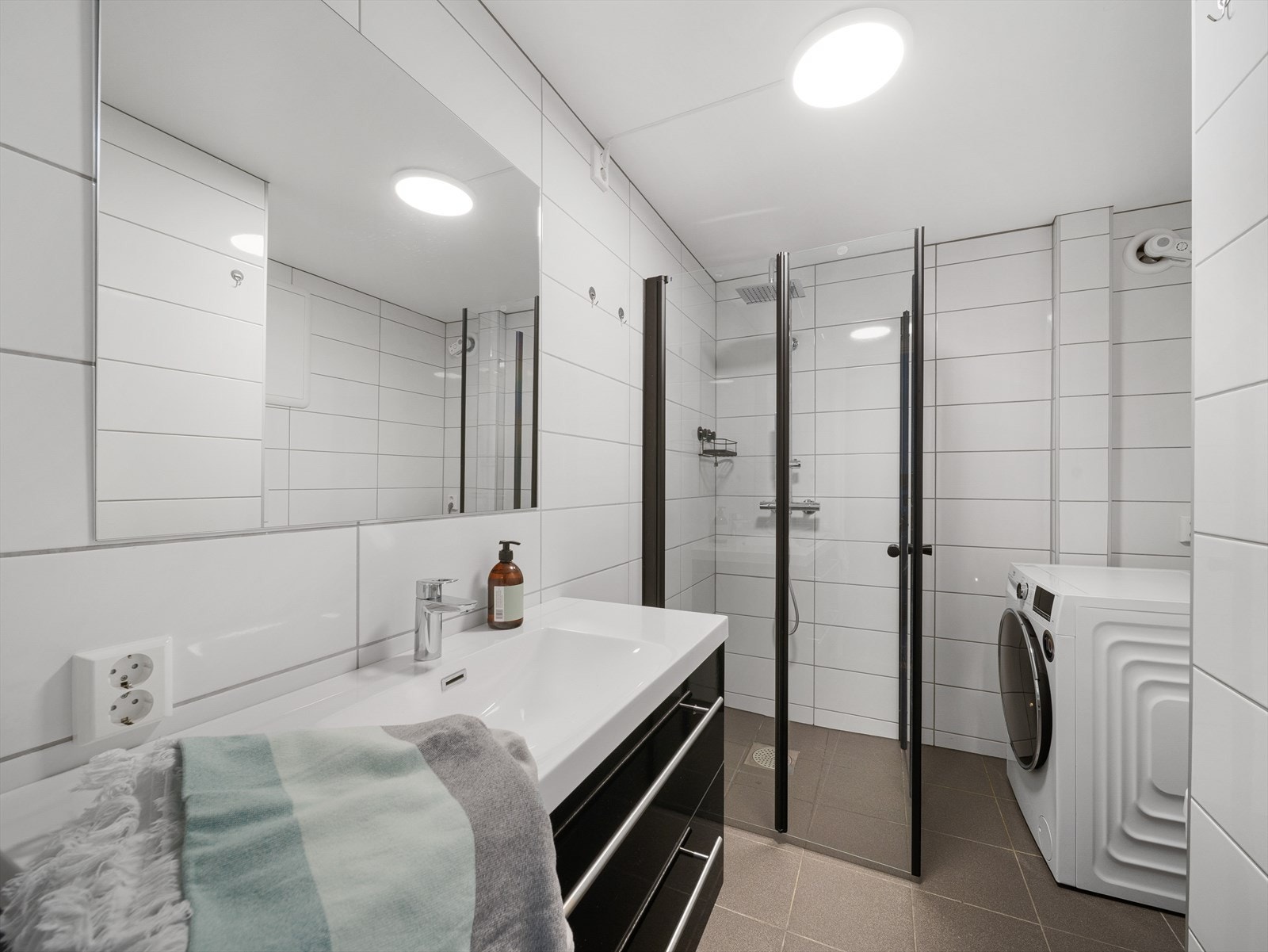 Badet ble pusset opp i 2022 og har fliser på gulv og vegger. Badet er innredet med baderomsinnredning med servant, dusj, vegghengt toalett og opplegg for vaskemaskin. Galleribilde