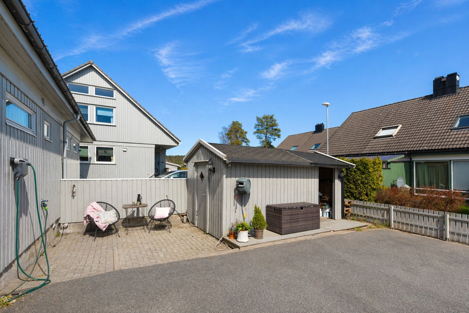 Asfaltert gårdsplass med biloppstillingsplass og en praktisk utebod for ekstra lagring. Galleribilde