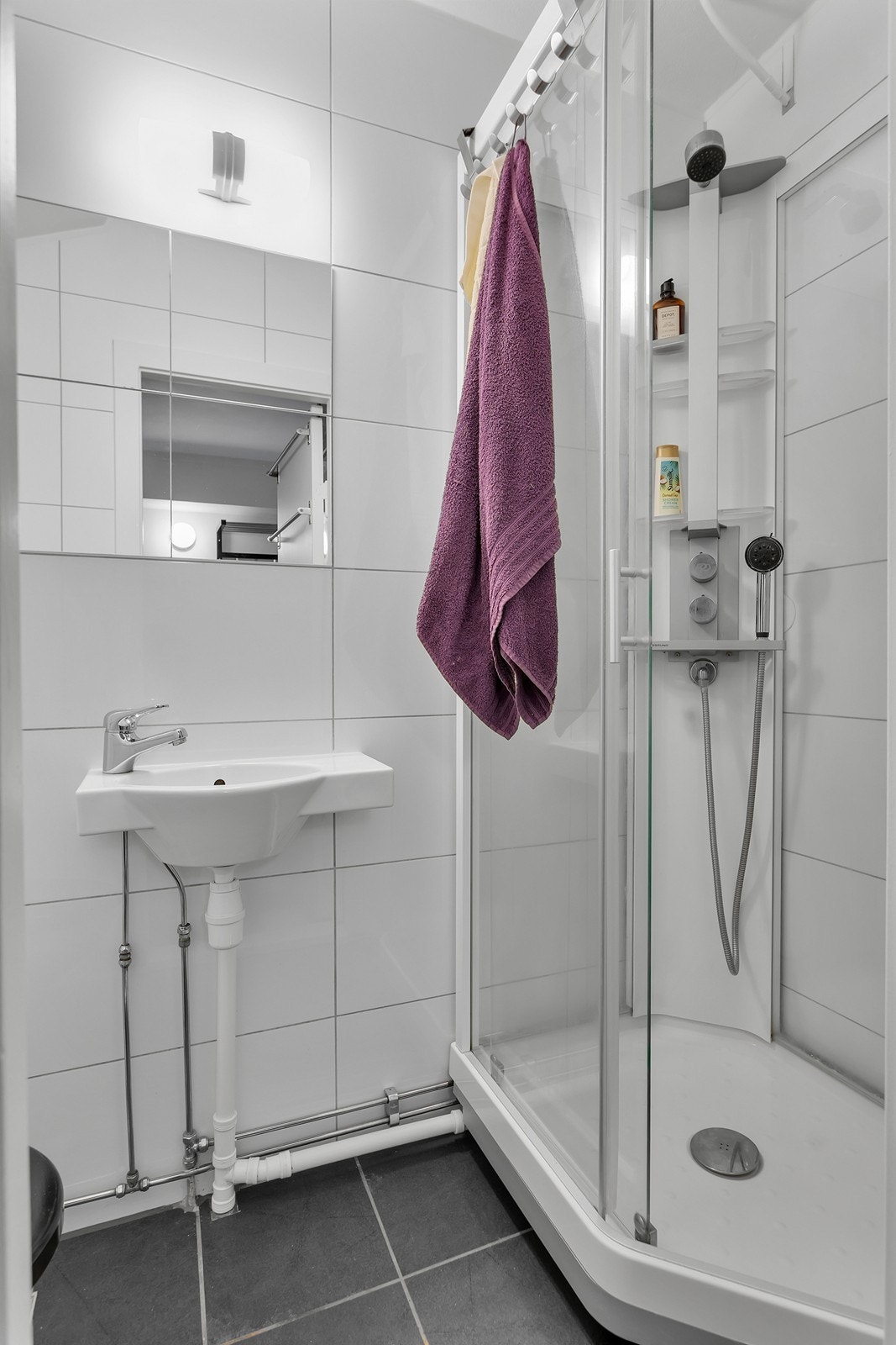 Pent bad som er innredet med servant, veggmontert toalett og dusjkabinett. Galleribilde
