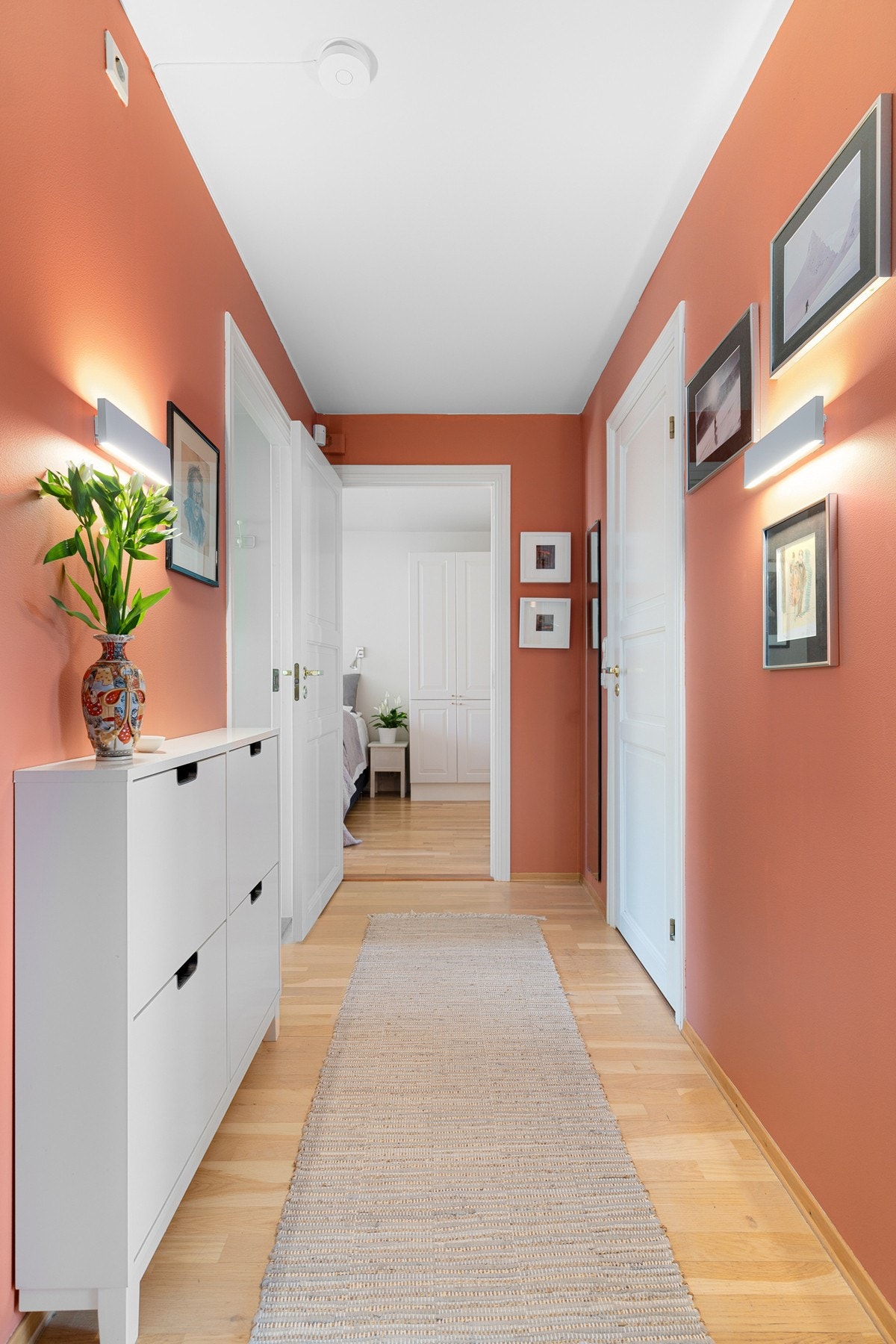 Lys og innbydende entré/gang med varme terrakottafargede vegger, kombinert med parkettgulv. Galleribilde