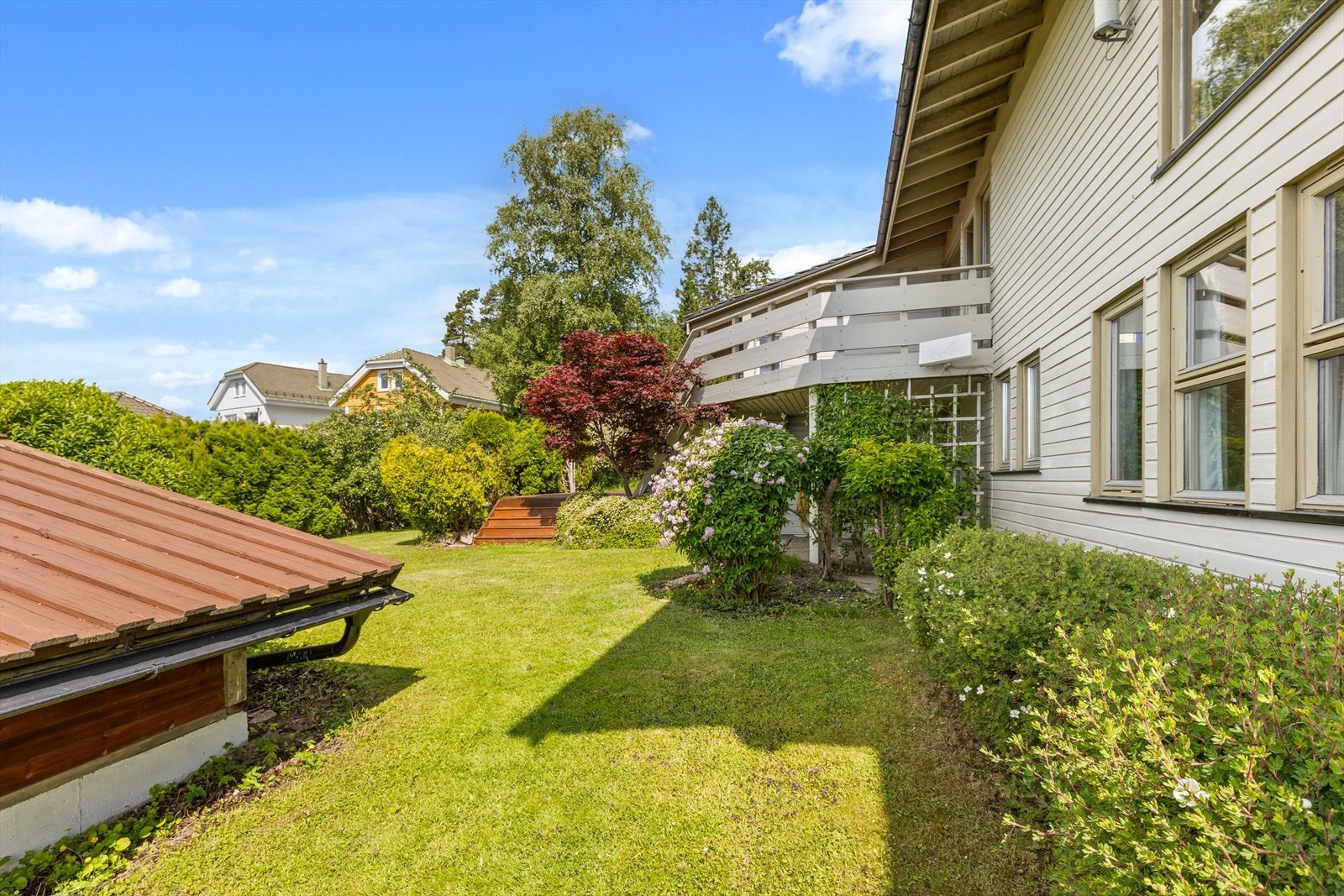 Hagen er en skjermet oase med terrasse, gressplen og vakker beplantning Galleribilde