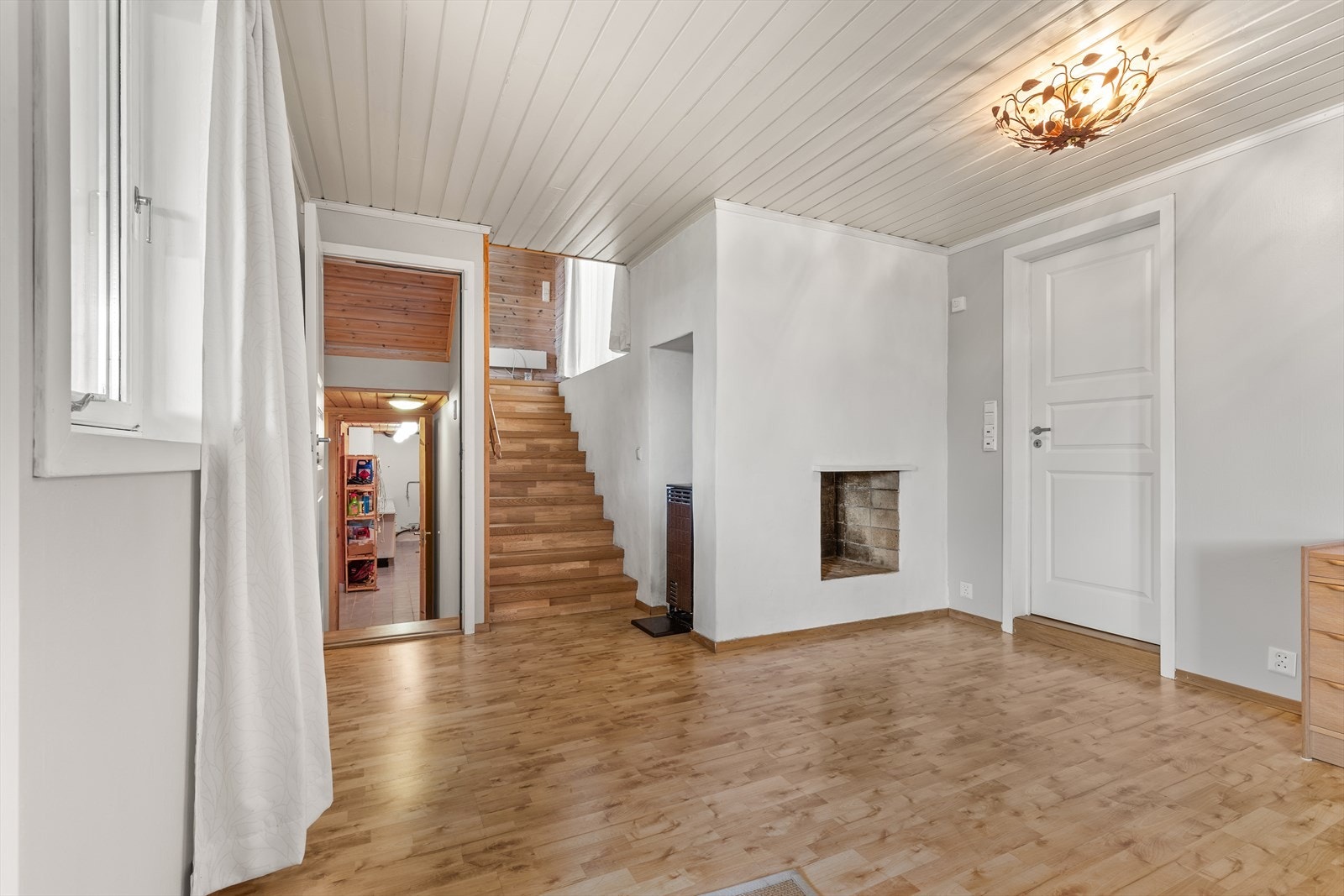 Stue i underetasje med vedovn, åpen peis og utgang til hage Galleribilde