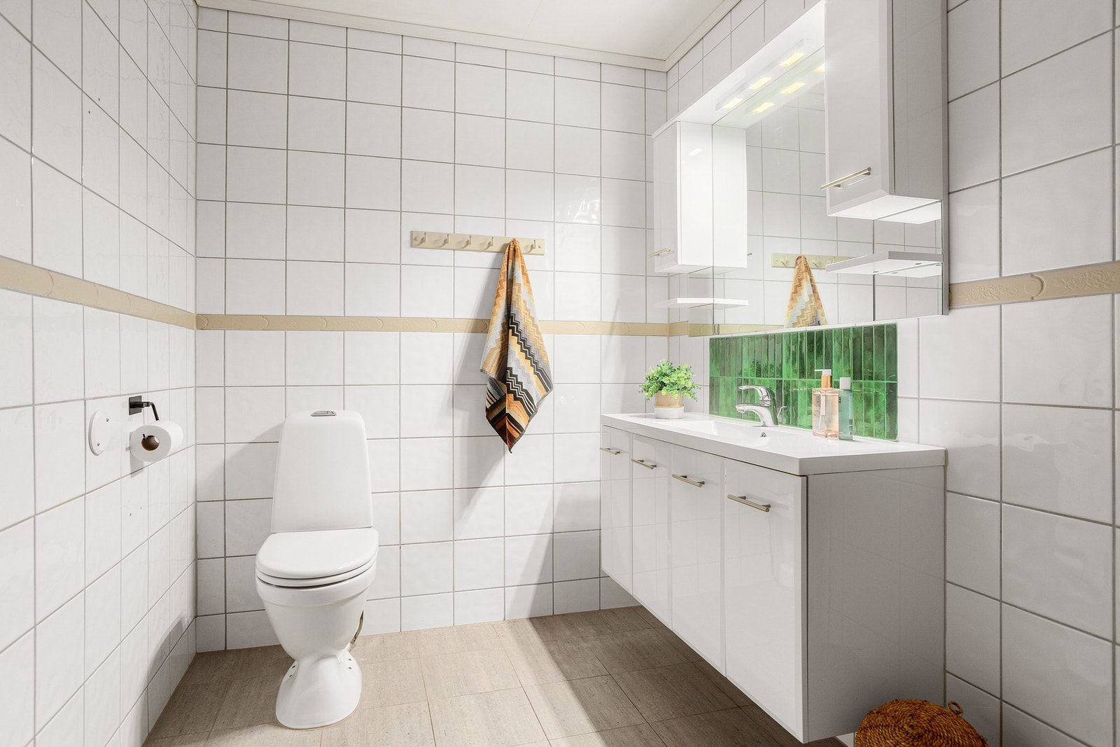 Badet i underetasjen er innredet med toalett, servant med underskuffer, speil, overskap og dusjkabinett. Galleribilde
