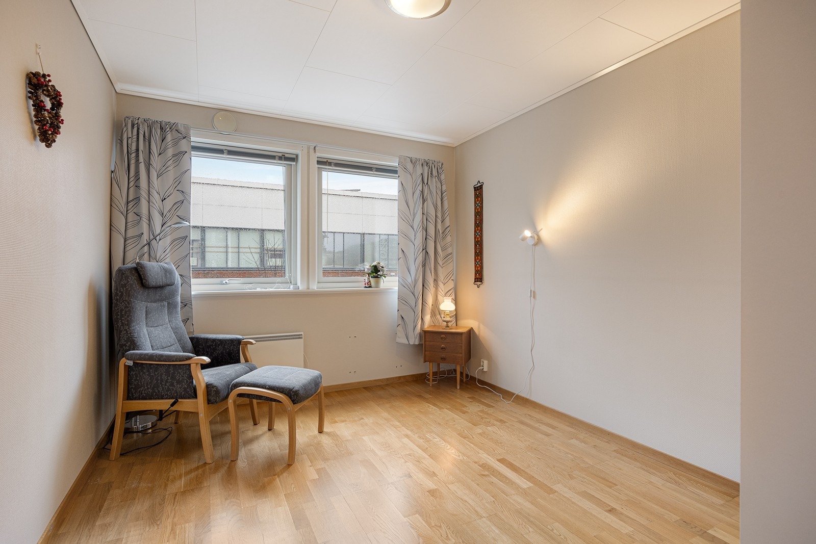 Leiligheten har et lyst soverom med parkettgulv, hvitmalte vegger, og god plass for dobbeltseng med tilhørende nattbord. Galleribilde