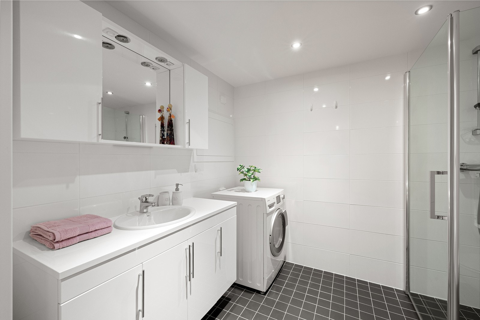 Boligen har et pent, flislagt bad med varmekabler i gulvog moderne downlights i himling. Her er det også opplegg for vaskemaskin og ett vegghengt vannklosett. Galleribilde