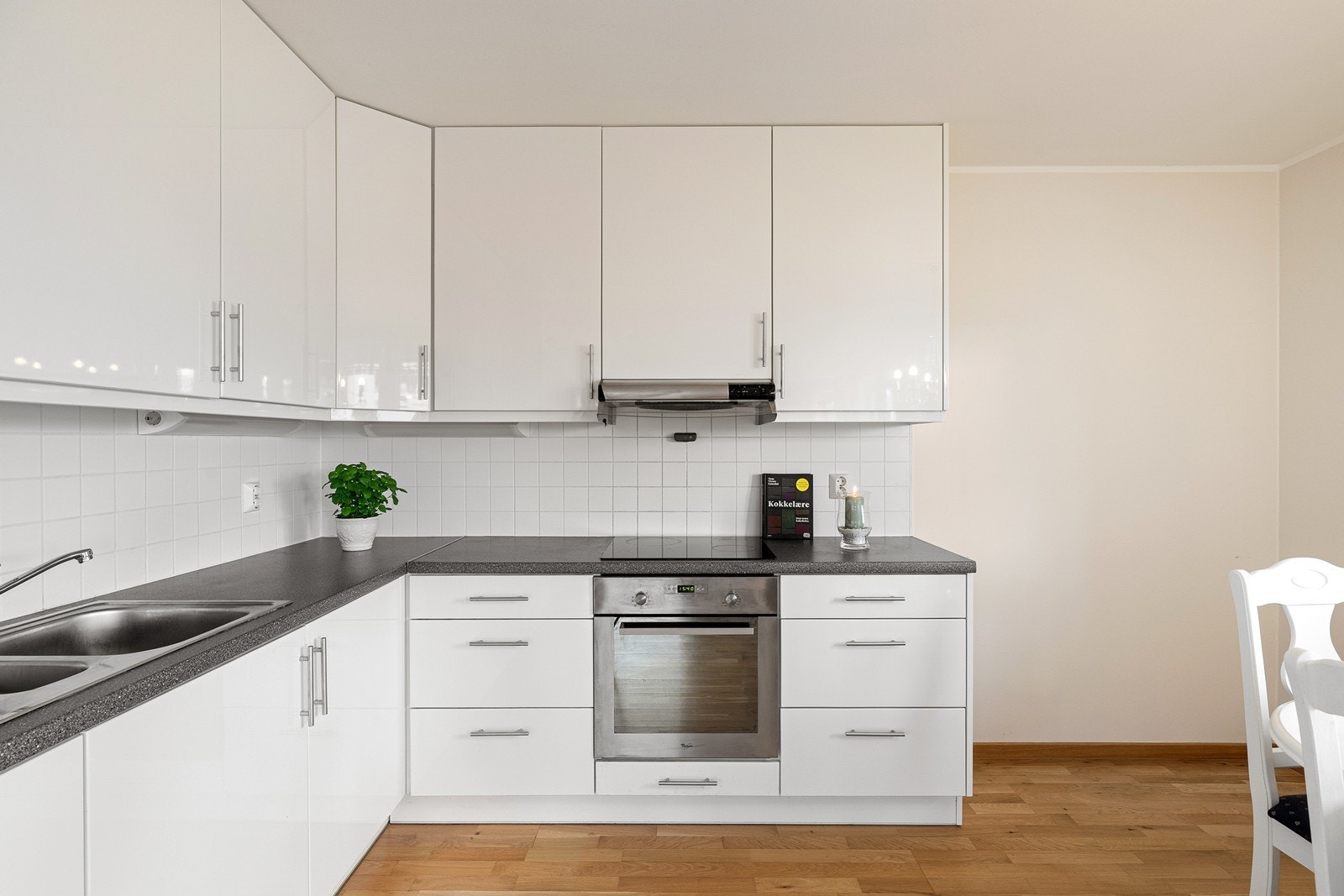 Et funksjonelt og stilrent kjøkken med god skapplass. Innredningen har laminert benkeplate, nedfelt oppvaskkum med ettgreps blandebatteri og dekorative fliser mellom over- og underskap. Galleribilde