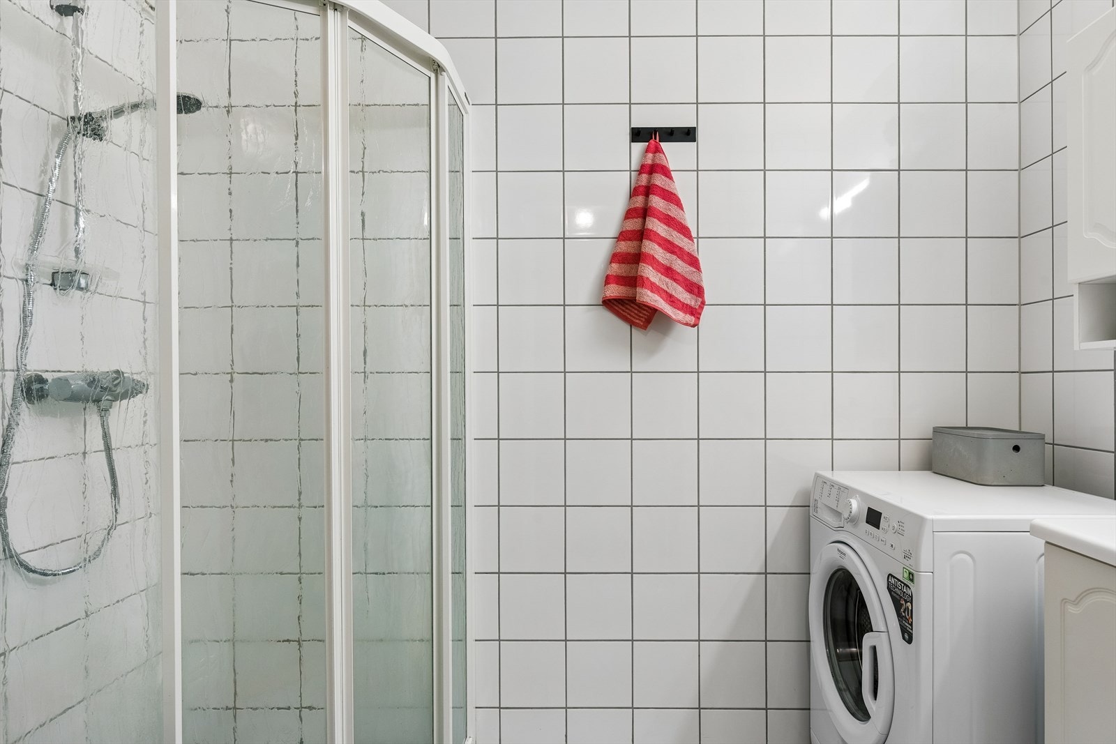 Badet er helfliset og har varmekabler i gulvet. Her er det også opplegg for vaskemaskin og en plassbesparende dusj med skyvedører. Galleribilde