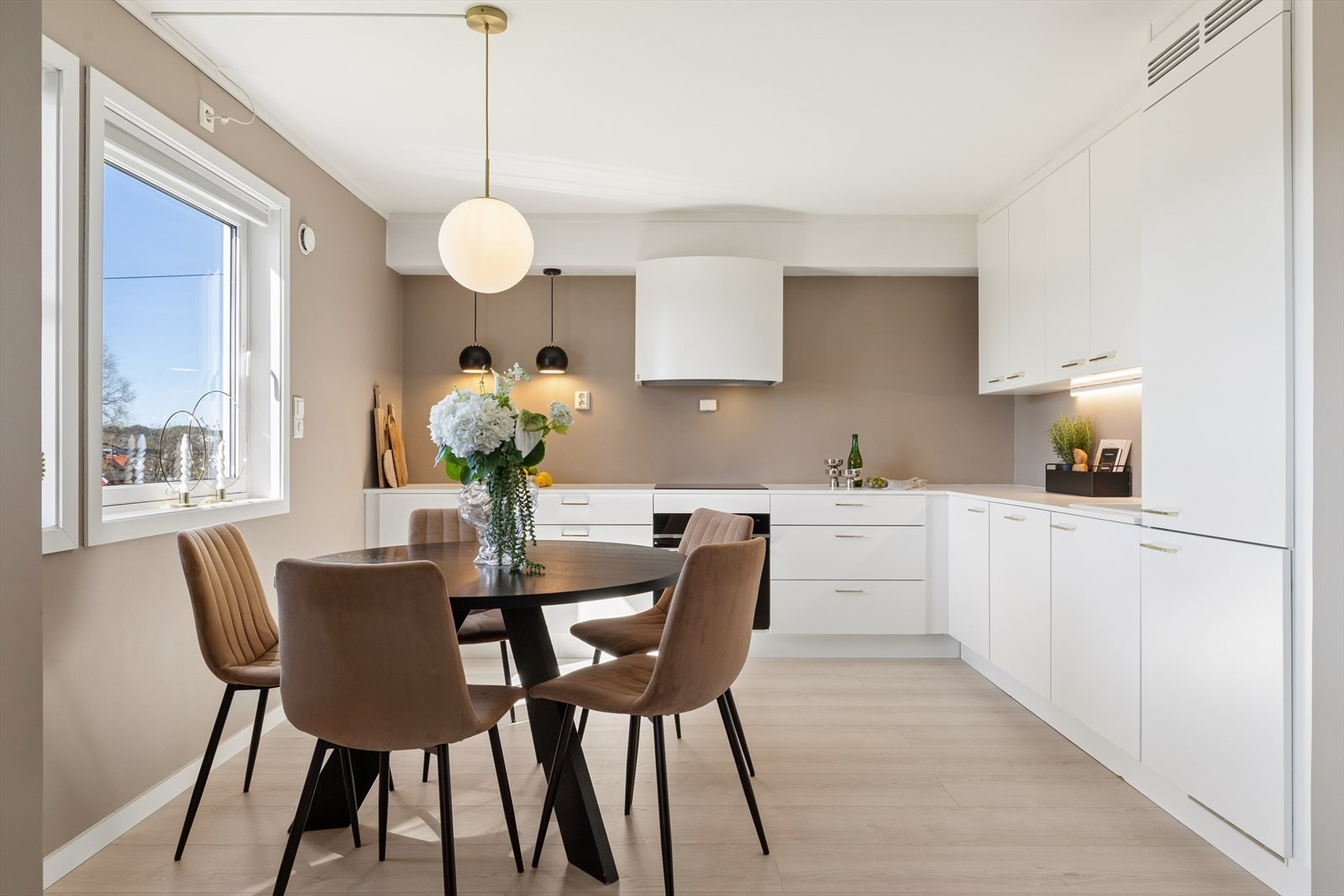 Åpent kjøkken med moderne og slette fronter som inviterer lyset inn gjennom vinduet. Galleribilde
