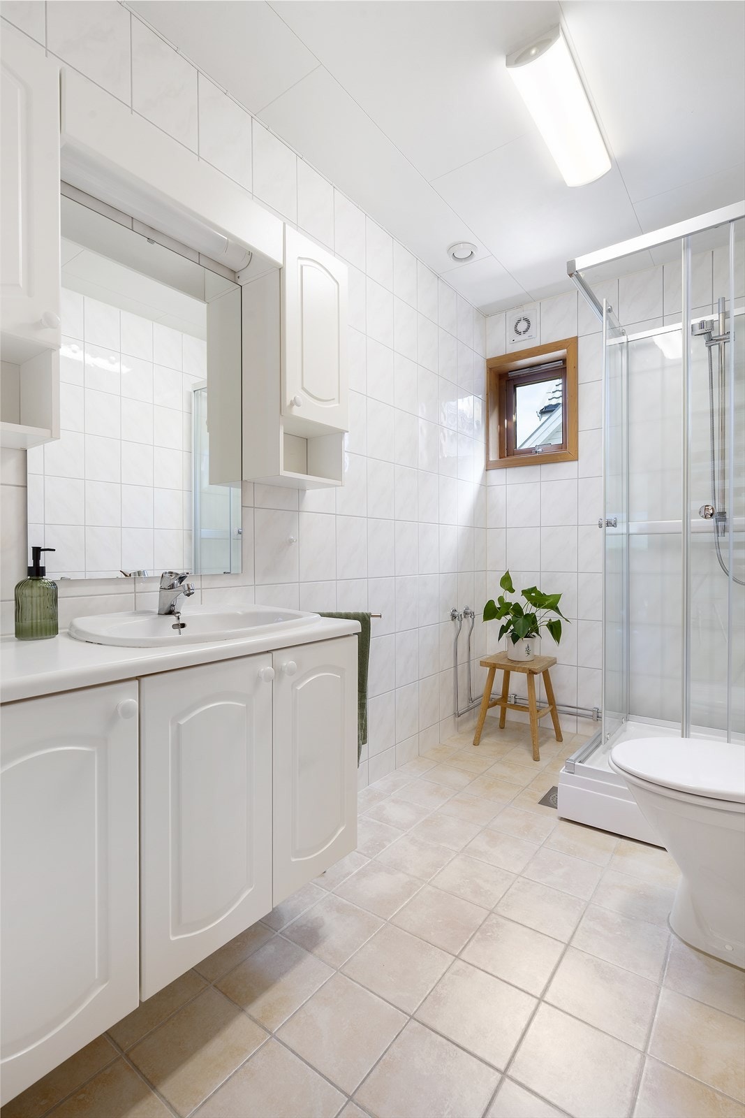 Badet har flislagte gulv og vegger, samt en elektrisk styrt vifte for ventilasjon. Galleribilde