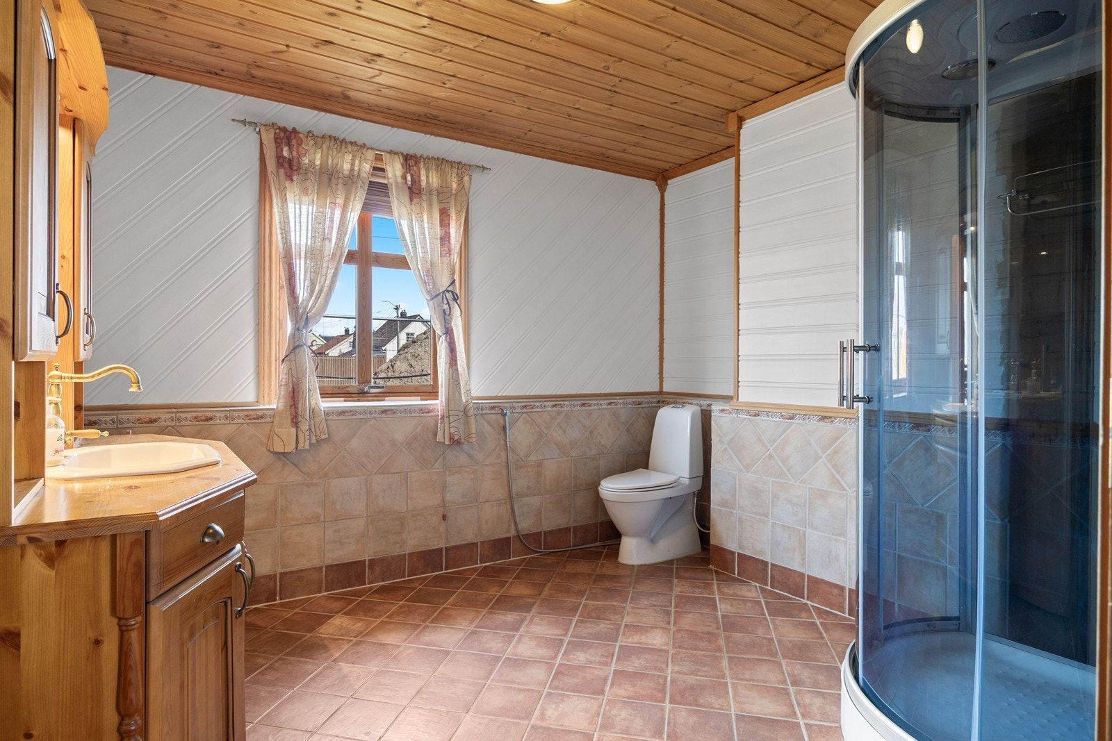 Badet er utstyrt med flislagte gulv og vegger kombinert med panel. Galleribilde