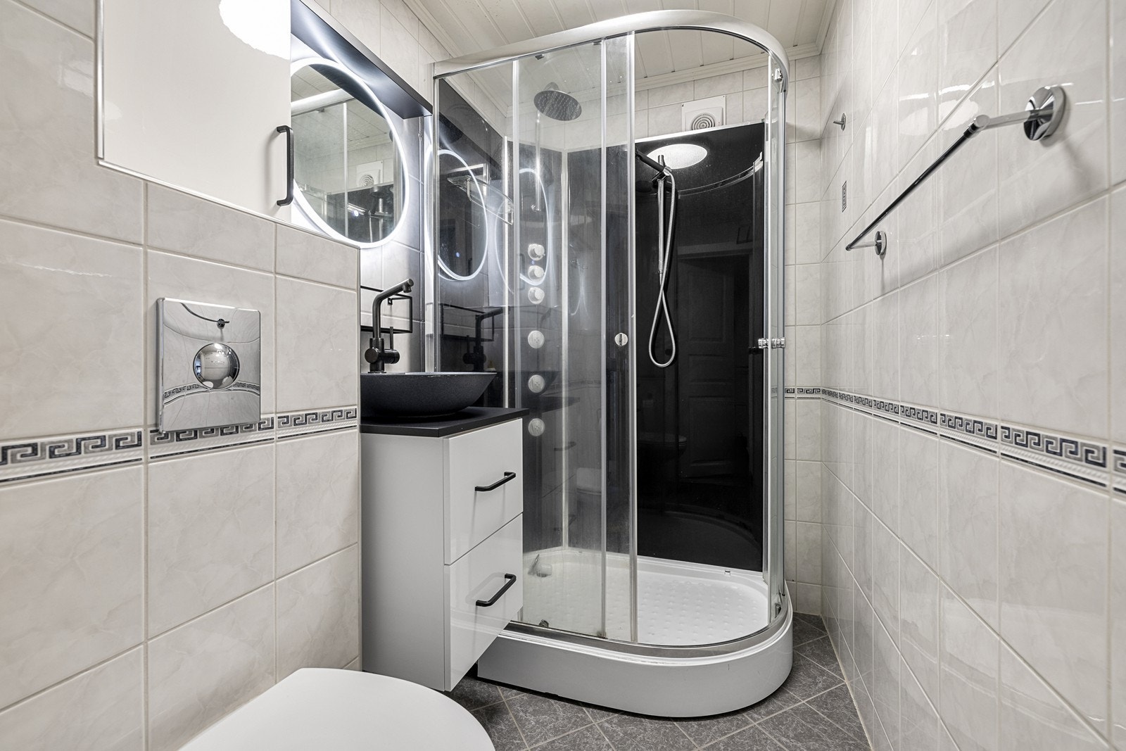 Badet er utstyrt med dusjkabinett, vegghengt toalett og servantinnredning. Rommet har mekanisk avtrekk. Galleribilde