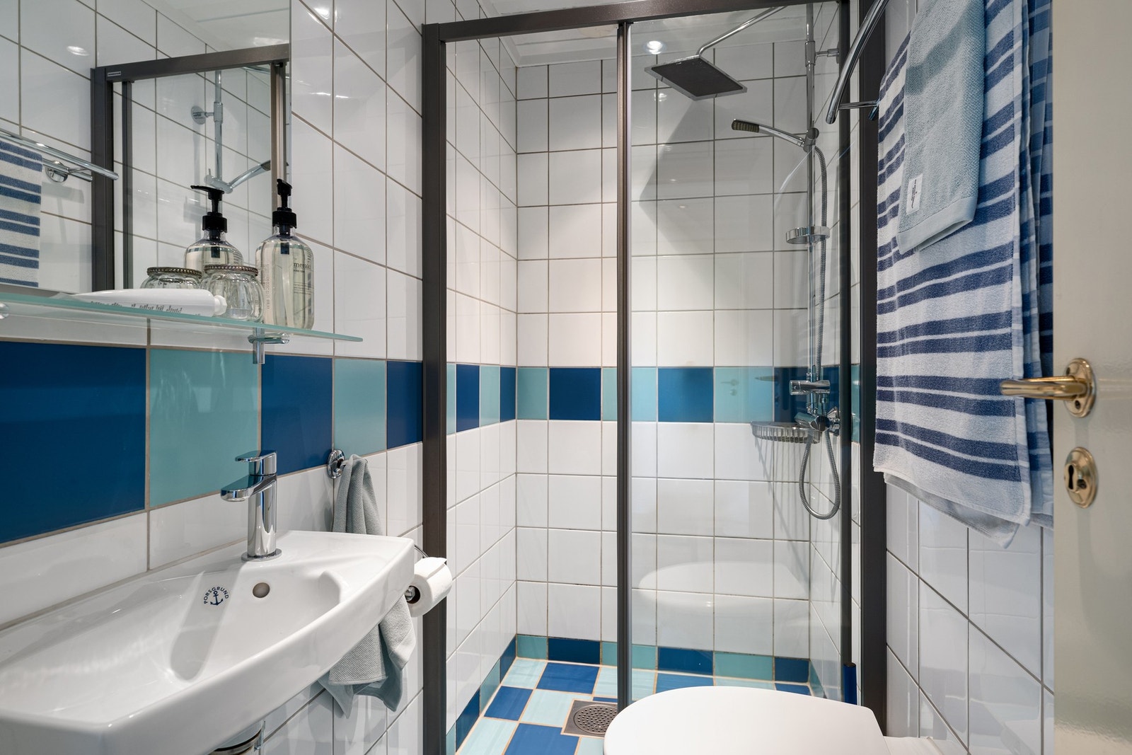Flislagt gulv med varmekabler og flislagte vegger. Porselensservant på vegg og speil. Vegghengt toalett. Dusjvegger. Galleribilde