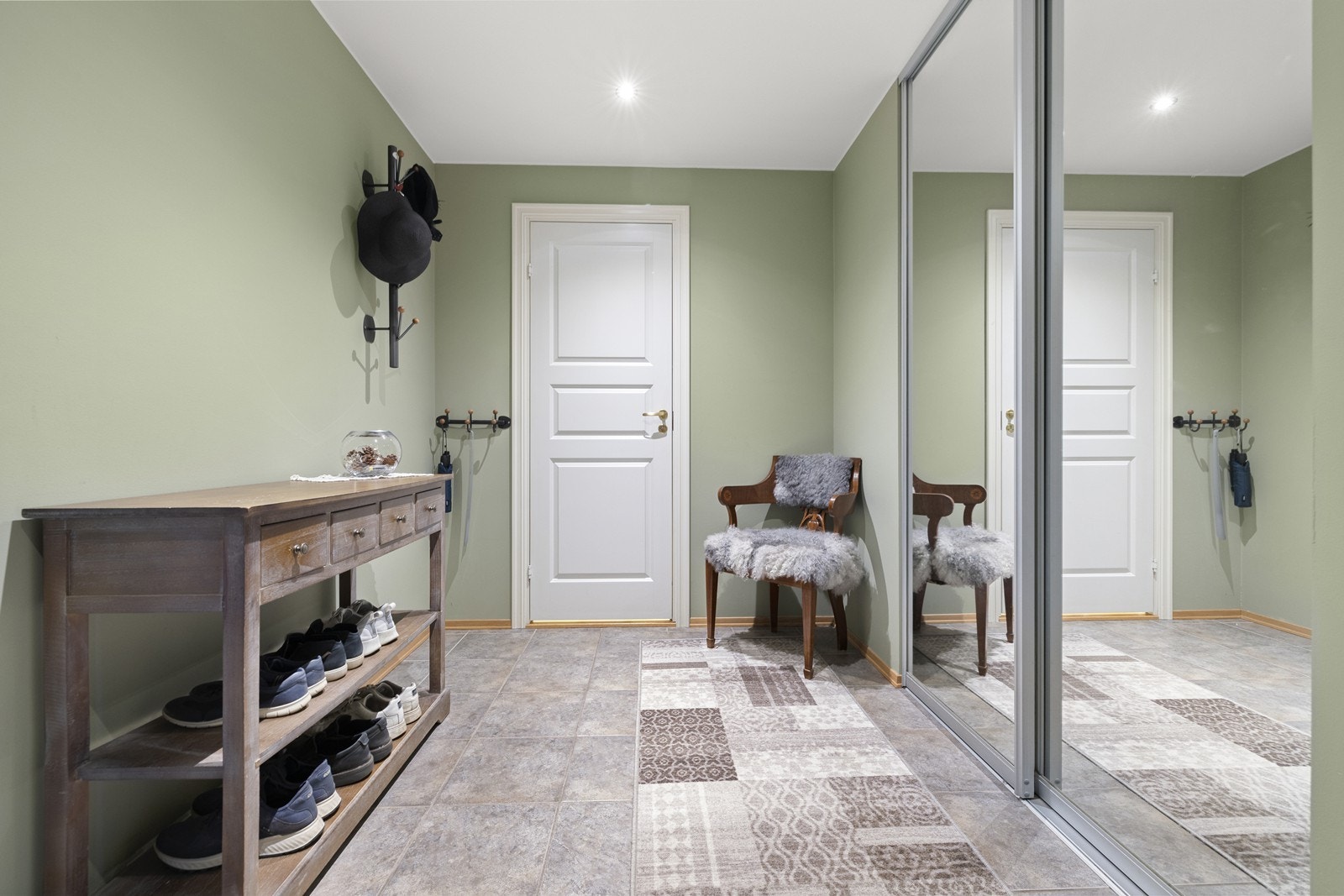 En stor skyvedørsgarderobe med speilfronter gir rikelig med oppbevaringsplass for yttertøy og sko. Galleribilde