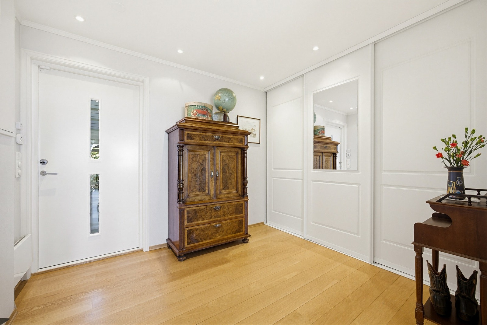 Et luftig og innbydende inngangsparti med stor skyvedørsgarderobe. Det er gjenomgående lys fra entrédøren til stuen og downlights i himlingen. Galleribilde
