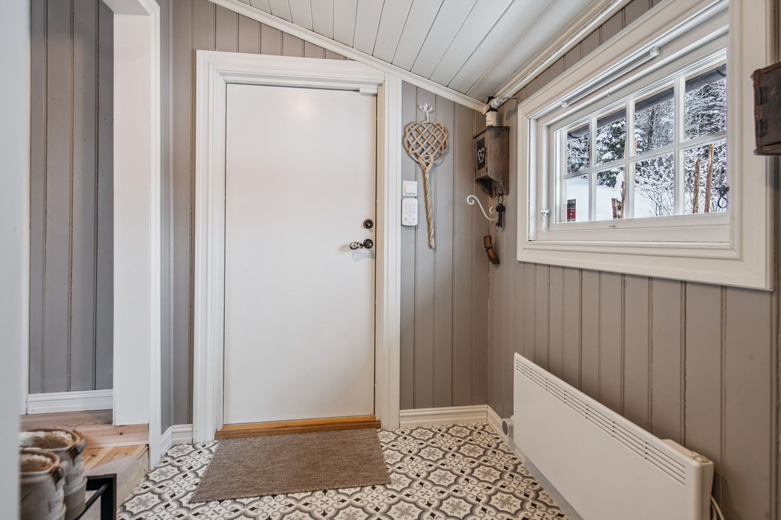 Inngangspartiet er praktisk med mønstret vinylgulv og panel på veggene. Galleribilde