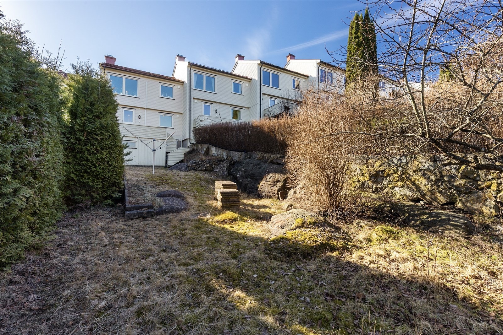 Fra terrassen er det adkomst ned til hagedel med gressplen og noe fjell i dagen som ligger fint skjermet med hekkbeplantning. Galleribilde