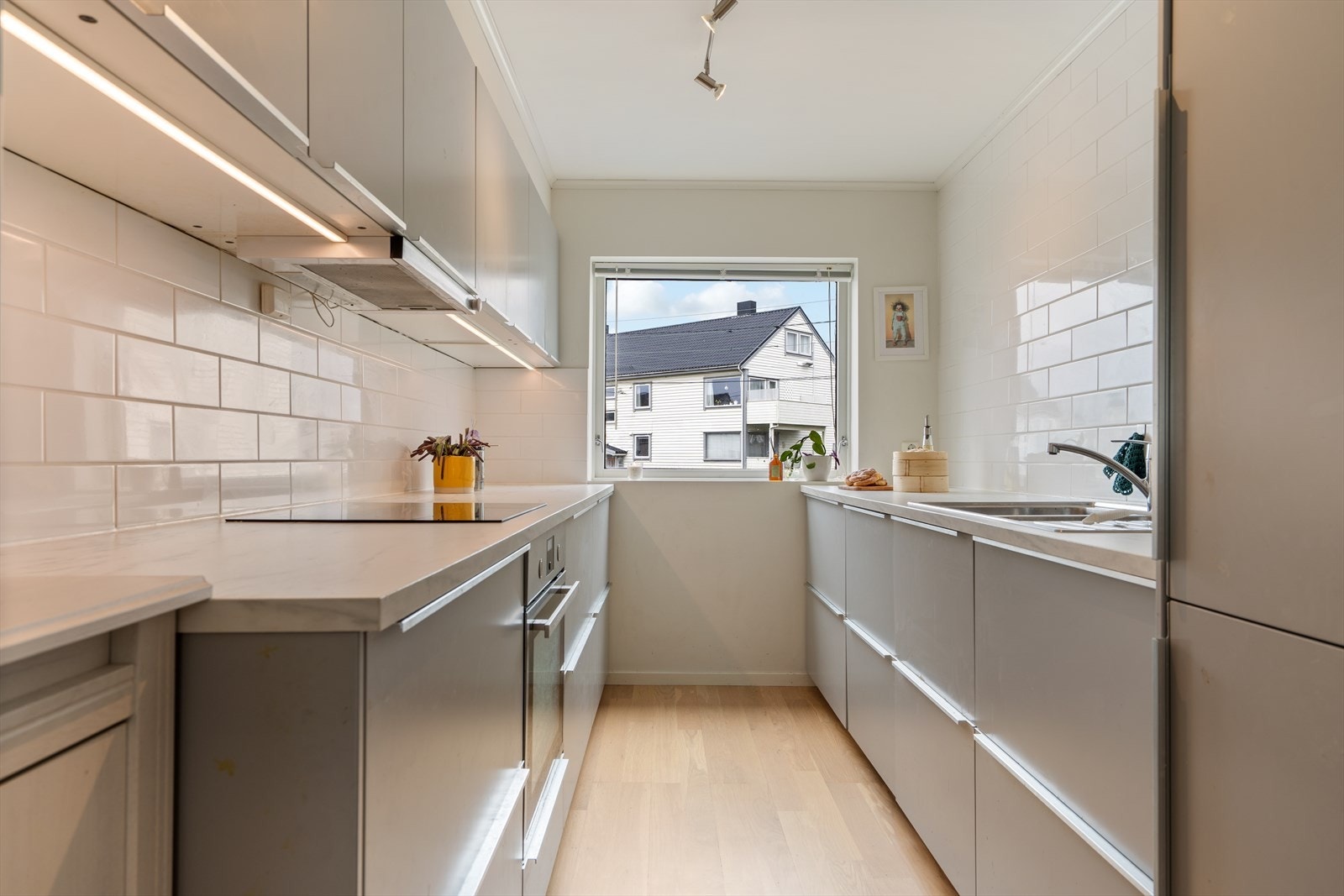 Kjøkkeninnredning med slette fronter og laminert benkeplate. Det er integrert oppvaskmaskin, kjøl/frys, platetopp og stekeovn. God skap- og benkplass. Galleribilde