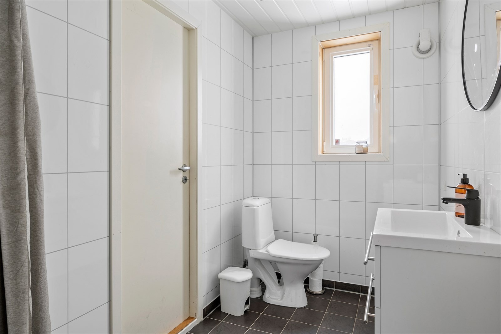 Badet i førsteetasjen ligger i bakkant av naustet, har flislagte gulvflater og baderomsplater, samt mekanisk avtrekk på vegg. Galleribilde