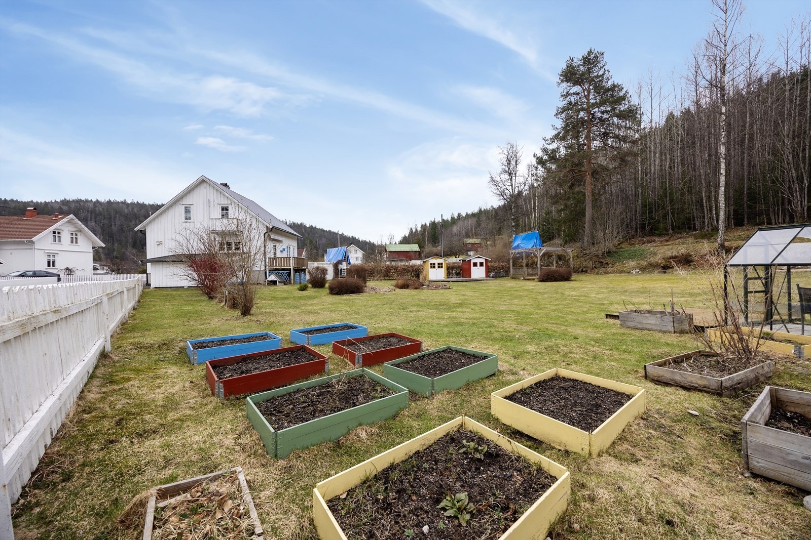 Tomten på ca. 1 mål er meget pent opparbeidet med plenarealer, blomsterbed og variert beplantning, samt gruset gårdsplass med parkering i carport. Galleribilde