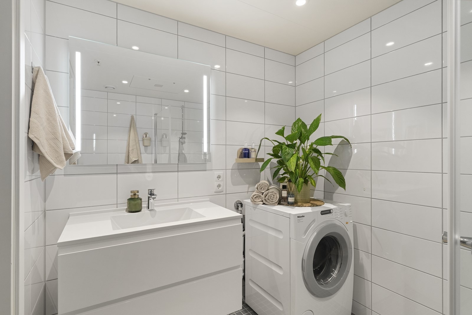 Badet byr på behagelig gulvvarme, vegghengt innredet servant, opplegg for vaskemaskin, vegghengt toalett og praktiske innfellbare dusjdører. Galleribilde