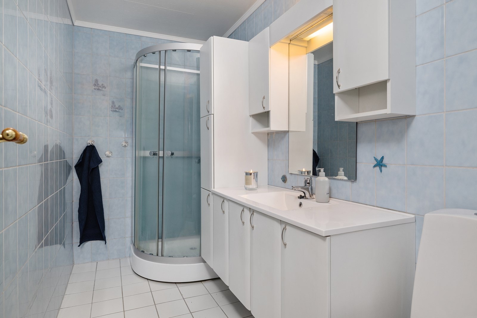 Badet er innredet med dusjkabinett, toalett og en heldekkende servant med underskap. Galleribilde