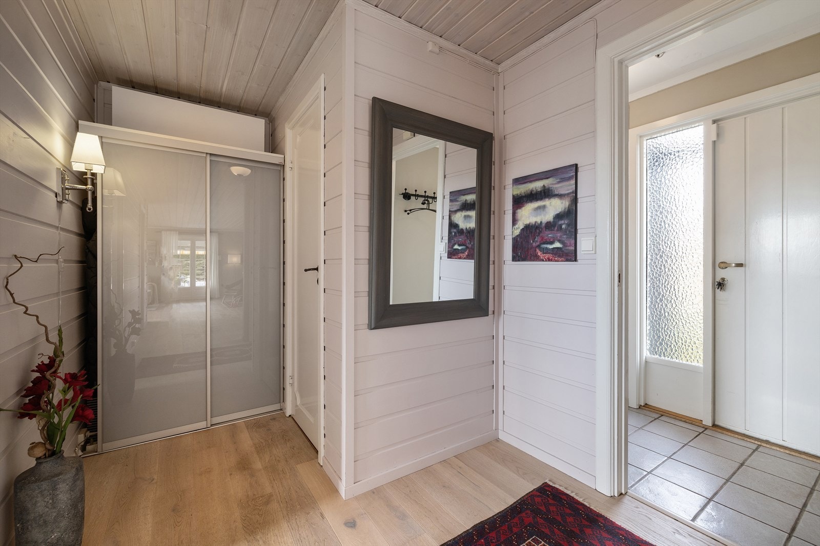 Vindfanget leder inn til en lys gang. Døren mellom rommene har glassfelt som slipper lyset gjennom. Galleribilde