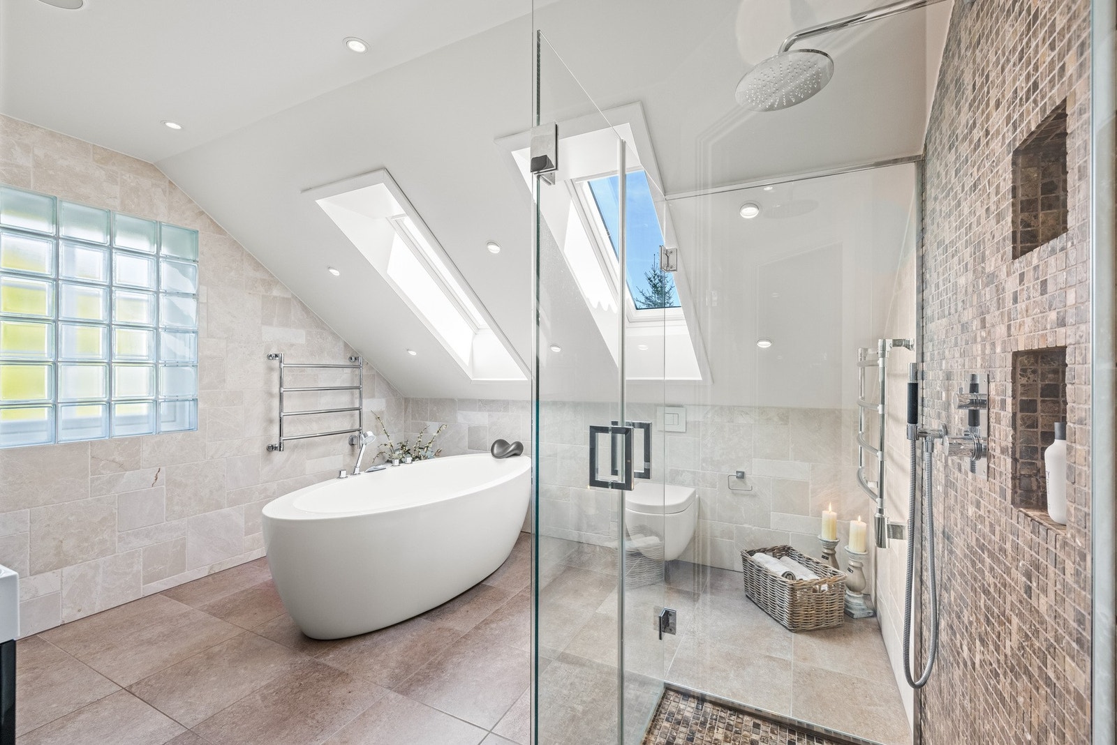 Badet er flislagt og innredet med dobbel servant, vegghengt wc, dusjnisje med glassvegger og et frittstående badekar. Galleribilde