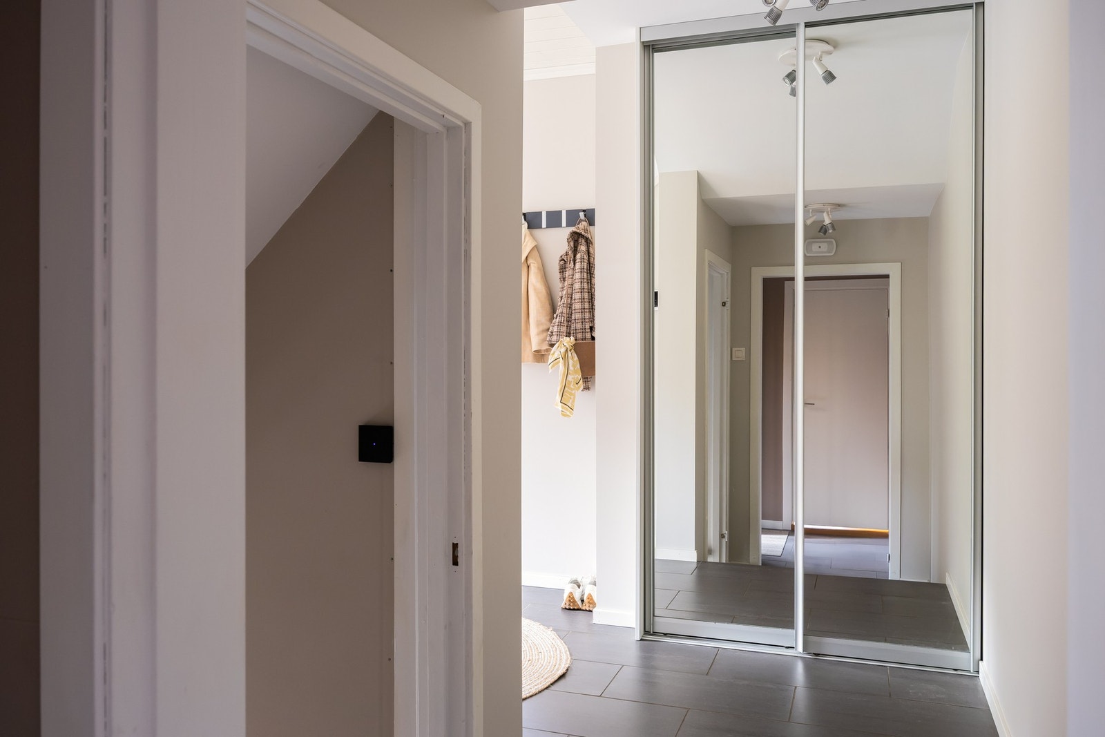 Hovedinngang i 1.etasje. Man kommer inn i en flislagt entré på 2m² og videre til en gang på 12m² utstyrt med skyvedørsgarderobe. Galleribilde