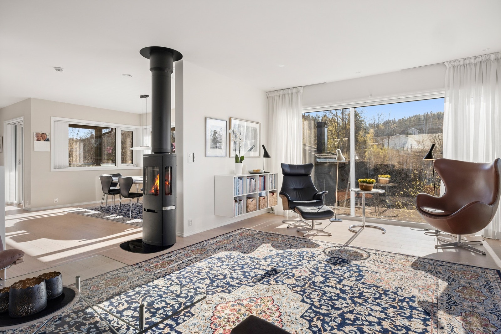Lys og åpen stue med store vinduer og peis. Galleribilde