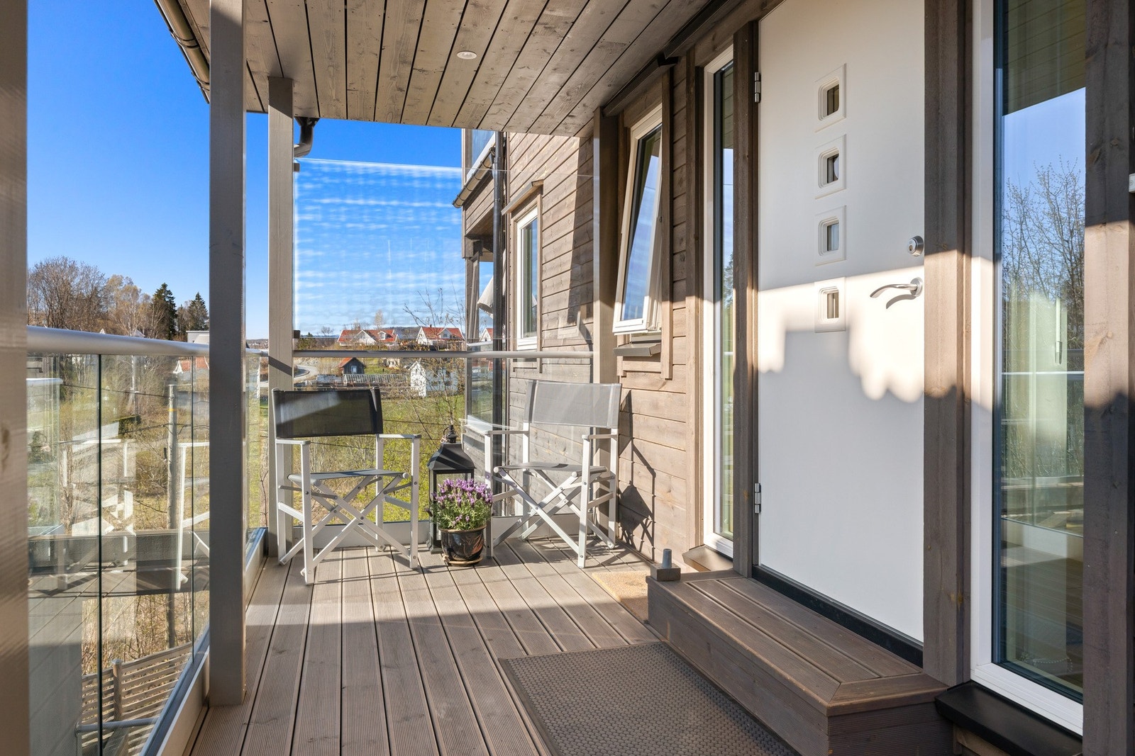 Overbygget inngangsparti med rekkverk i glass og utsikt mot nabolaget. Galleribilde